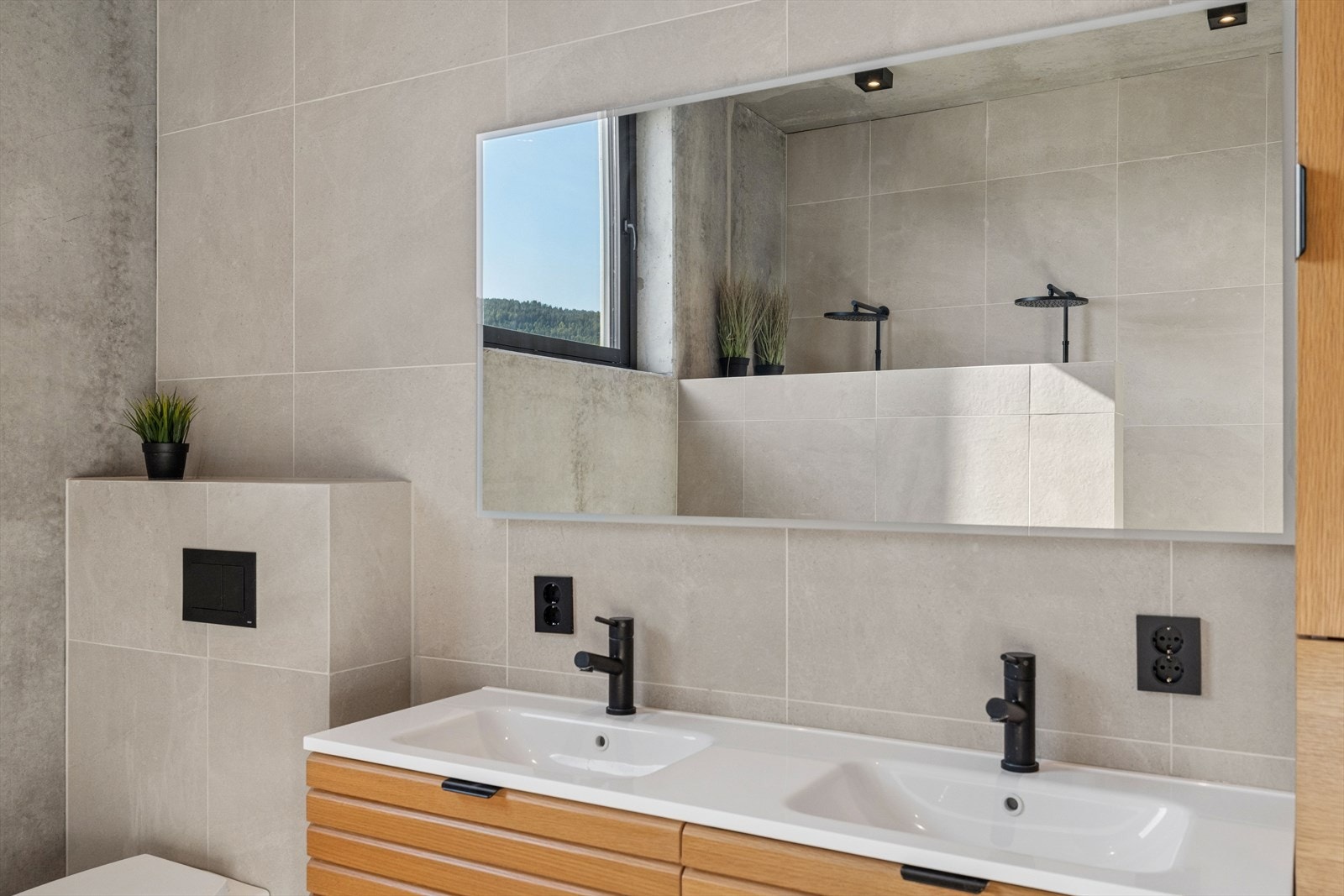 Badet er innredet med dobbel servantinnredning, vegghengt toalett og to separate dusjsoner. Galleribilde