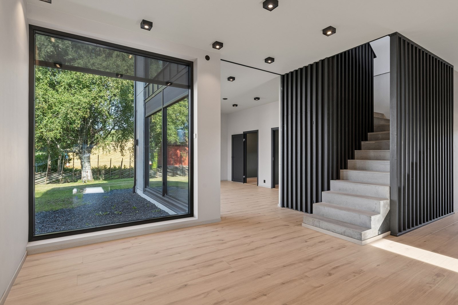 Den sentralt plasserte betongtrappen fremstår som et markant arkitektonisk element. Trappen er utført med støpte betongtrinn og mørkt spilerekkverk i tre, og binder etasjene sammen både visuelt og funksjonelt. Galleribilde