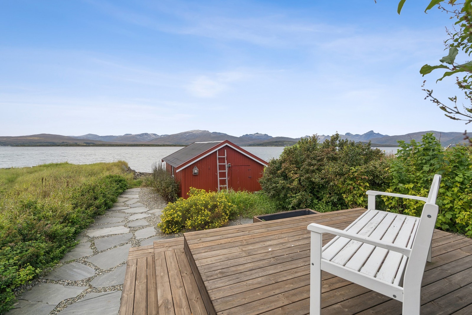 Uteplass med utsikt over fjorden, med naustet i forgrunnen. Galleribilde