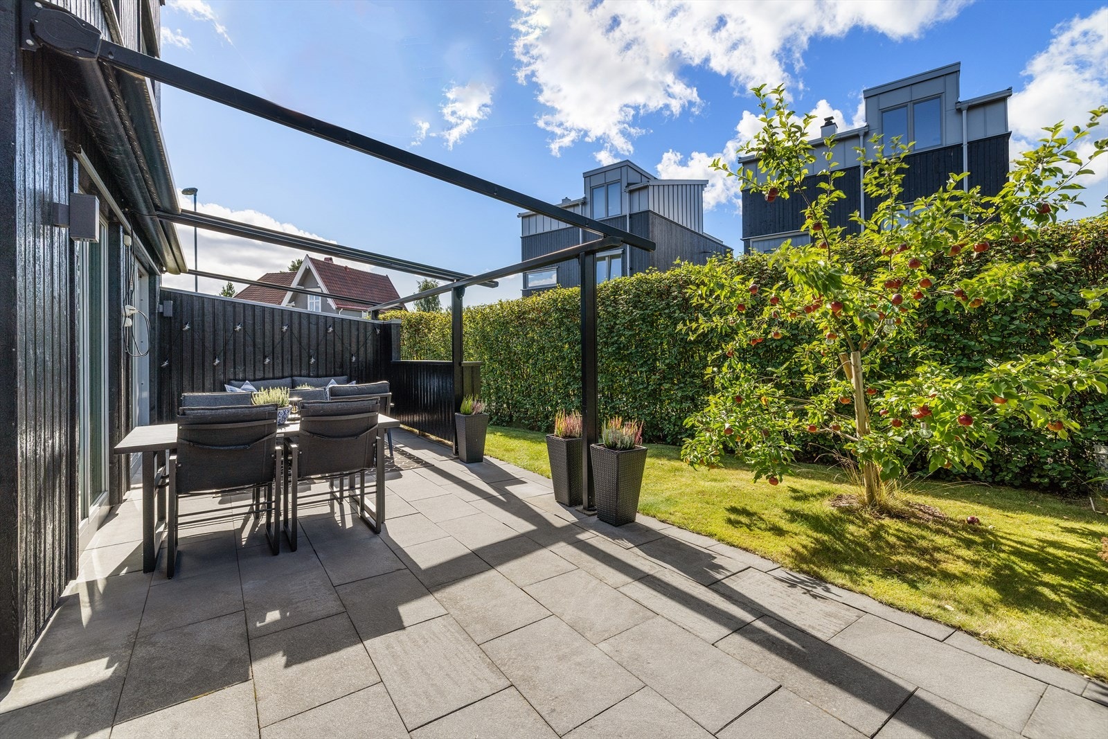Skjermet markterrasse med betongheller og god plass til utendørs spisebord. Galleribilde