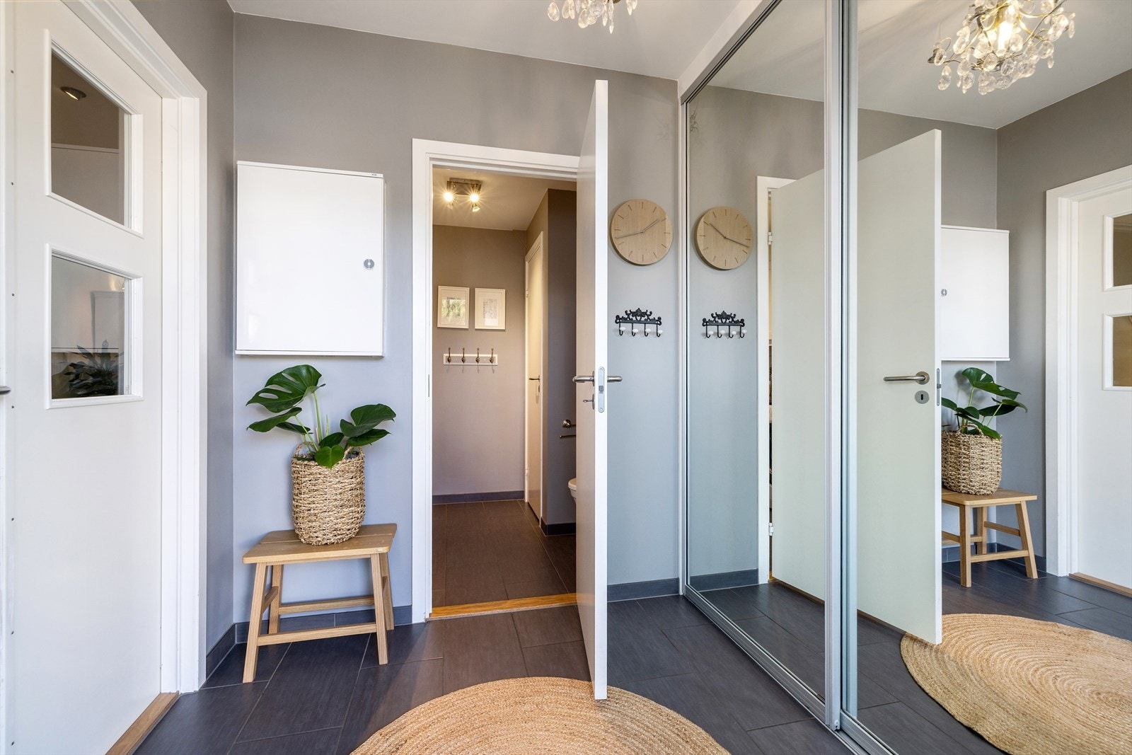 Romslig hall med flislagt gulv og stor skyvedørsgarderobe med speilfronter. Galleribilde