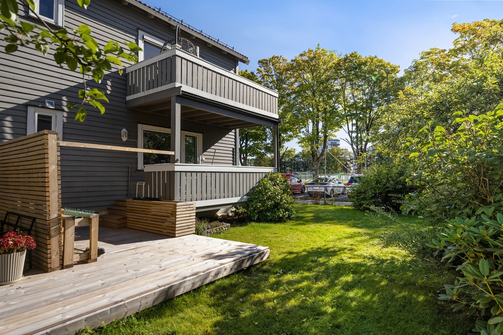 Felles hagearealer rammer inn bygningen. Leilighetens veranda ligger i andre etasje; terrassen på bakkeplan følger ikke denne andelen. Galleribilde