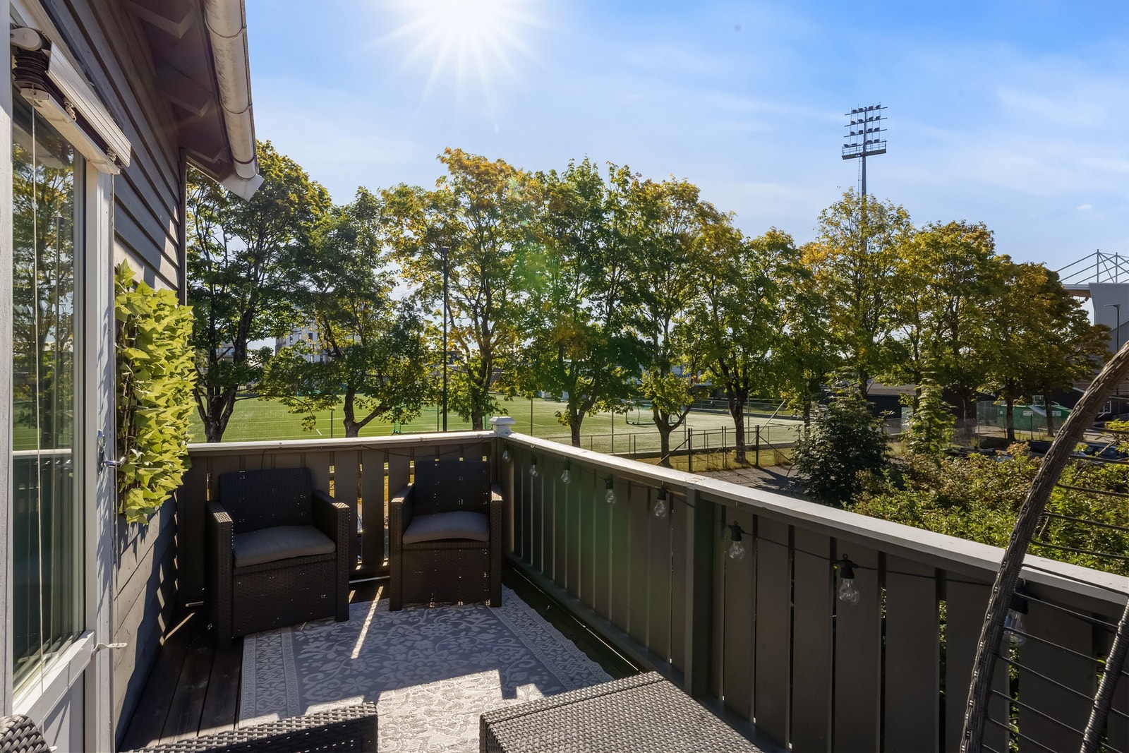 Verandaen har plass til sittegruppe og planter, med utsyn mot trær og idrettsanlegget på Melløs. Galleribilde