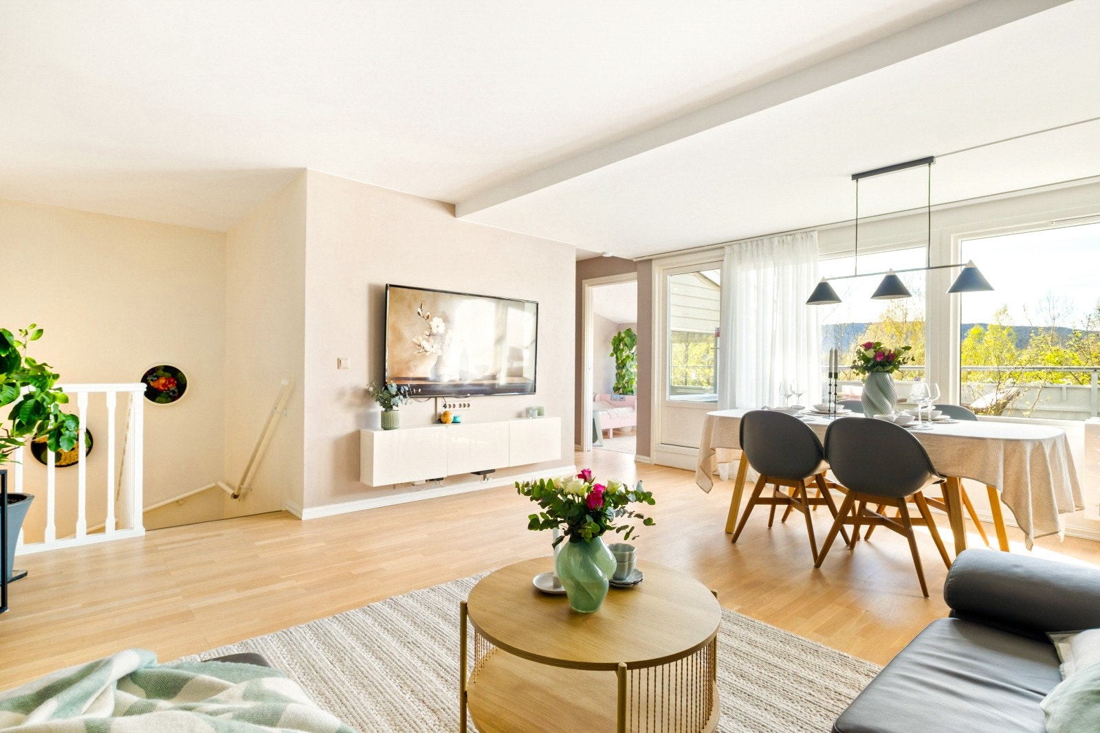En lys og luftig stue med store vindusflater, god plass til både sofagruppe og spisebord og en fin kontakt med uteplassen Galleribilde