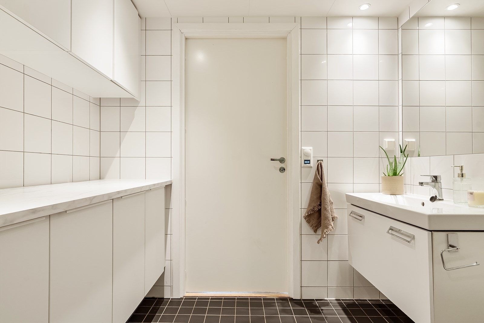 Baderomsinnredningen er bestående av servant med skuffeseksjon, vegghengt klosett, dusjhjørne med svingbare glassdører og opplegg for vaskemaskin. Galleribilde