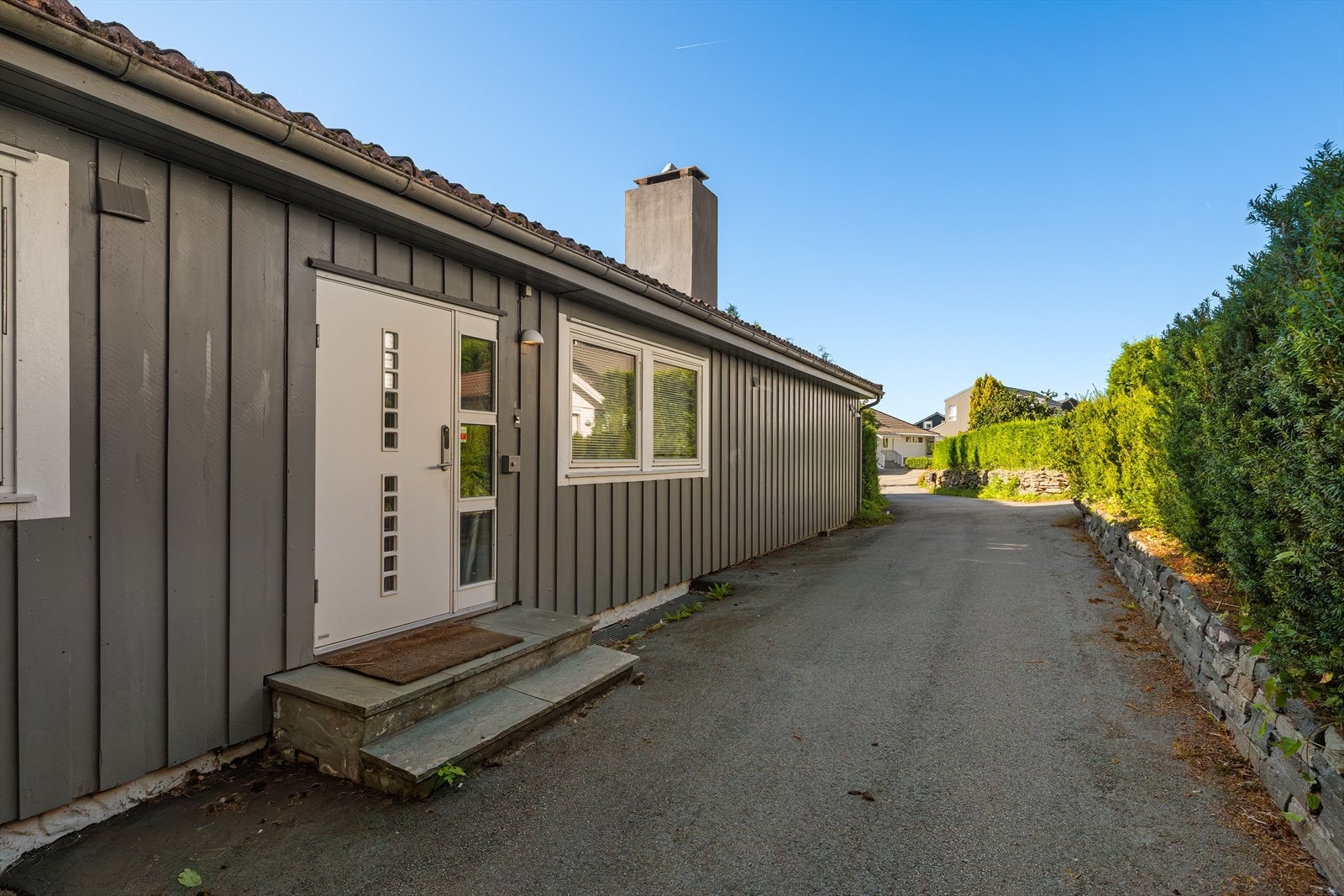 Inngangsparti med skifertrinn og asfaltert gårdsrom. Galleribilde