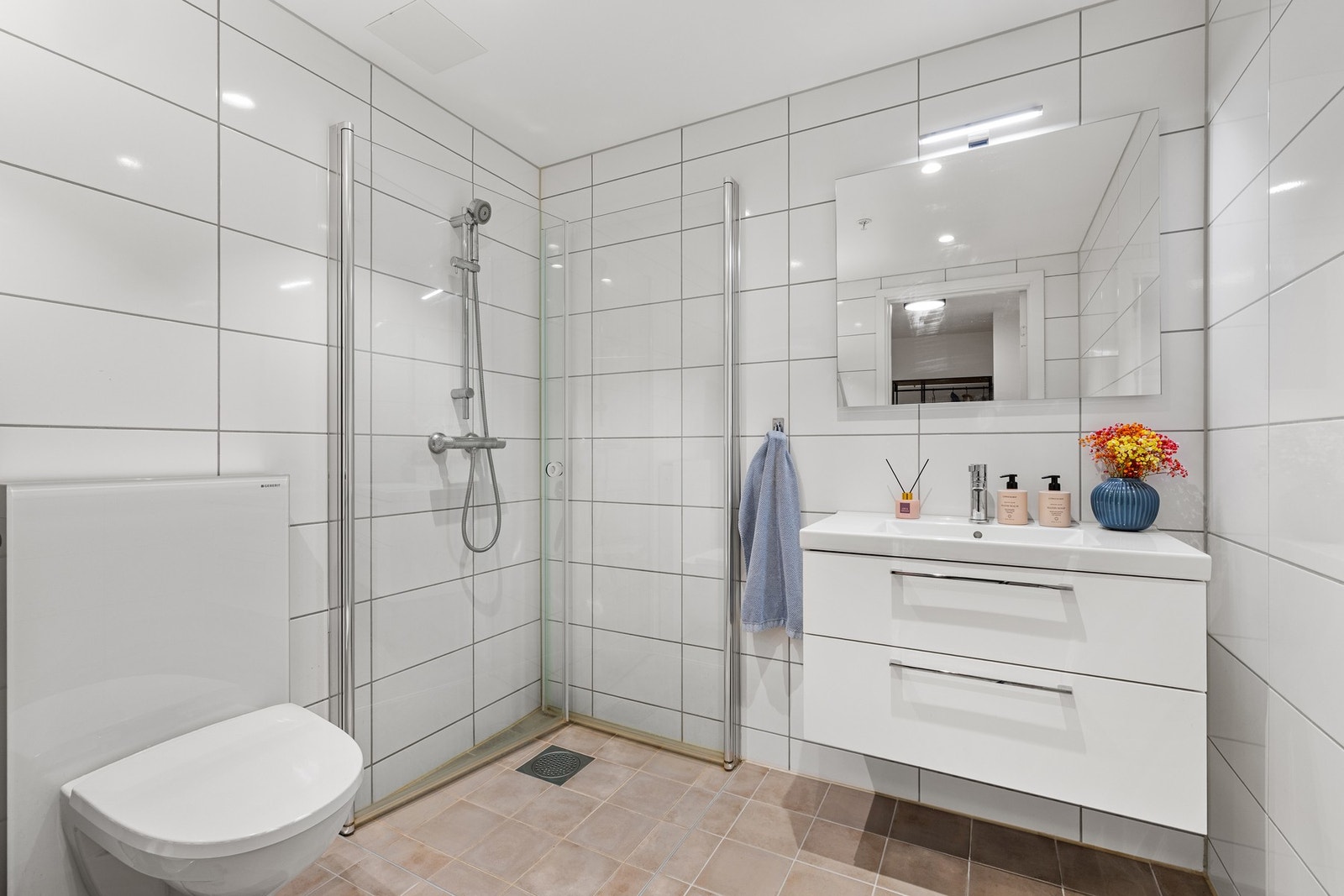 Badet har dusjhjørne, vegghengt toalett og opplegg for vaskemaskin og tørketrommel. Galleribilde