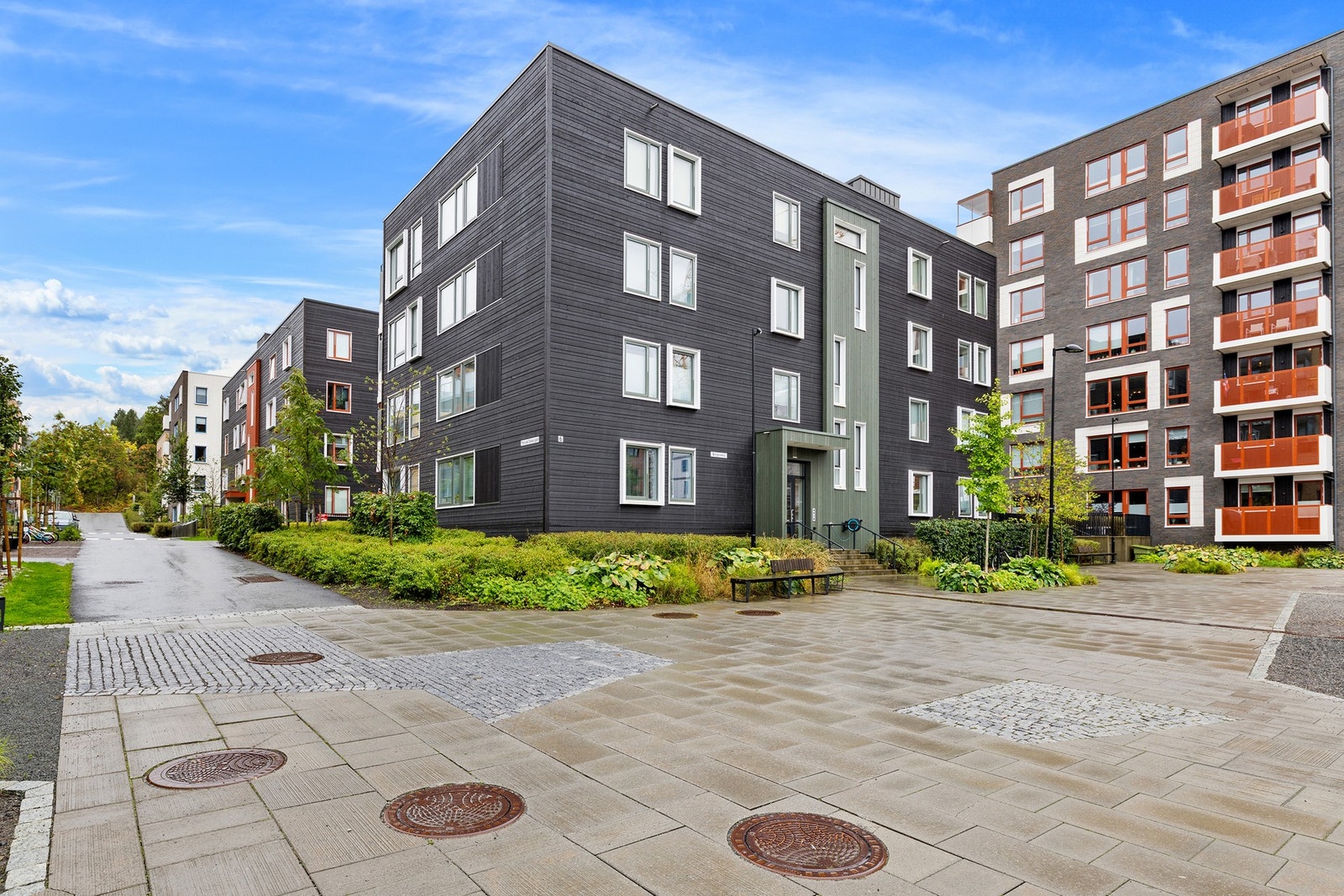 Pent opparbeidede uteområder med grønne tun, sitteplasser og lekeapparater. Galleribilde