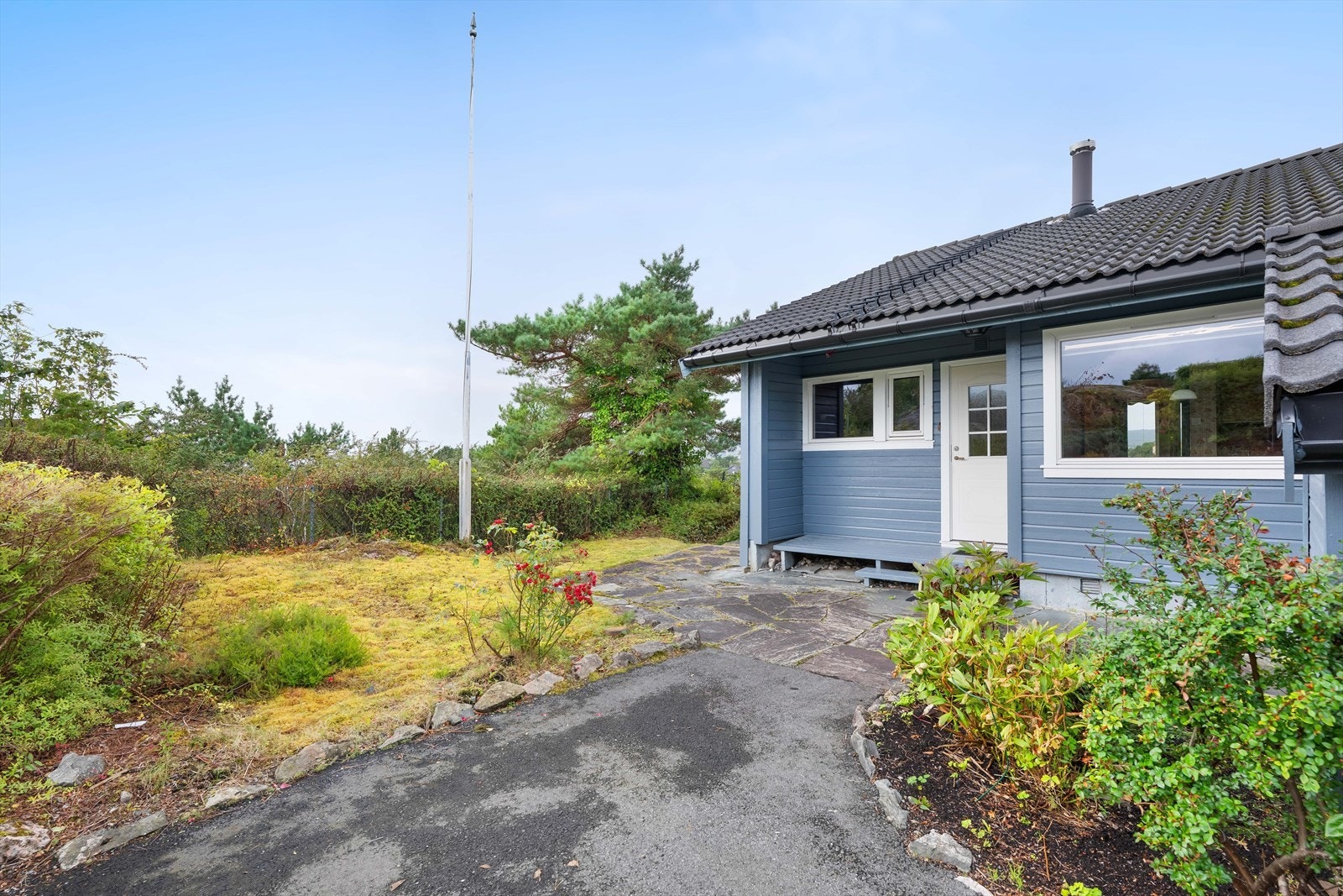 Hellelagt inngangsparti og opparbeidet tomt med plen og beplantning. Galleribilde