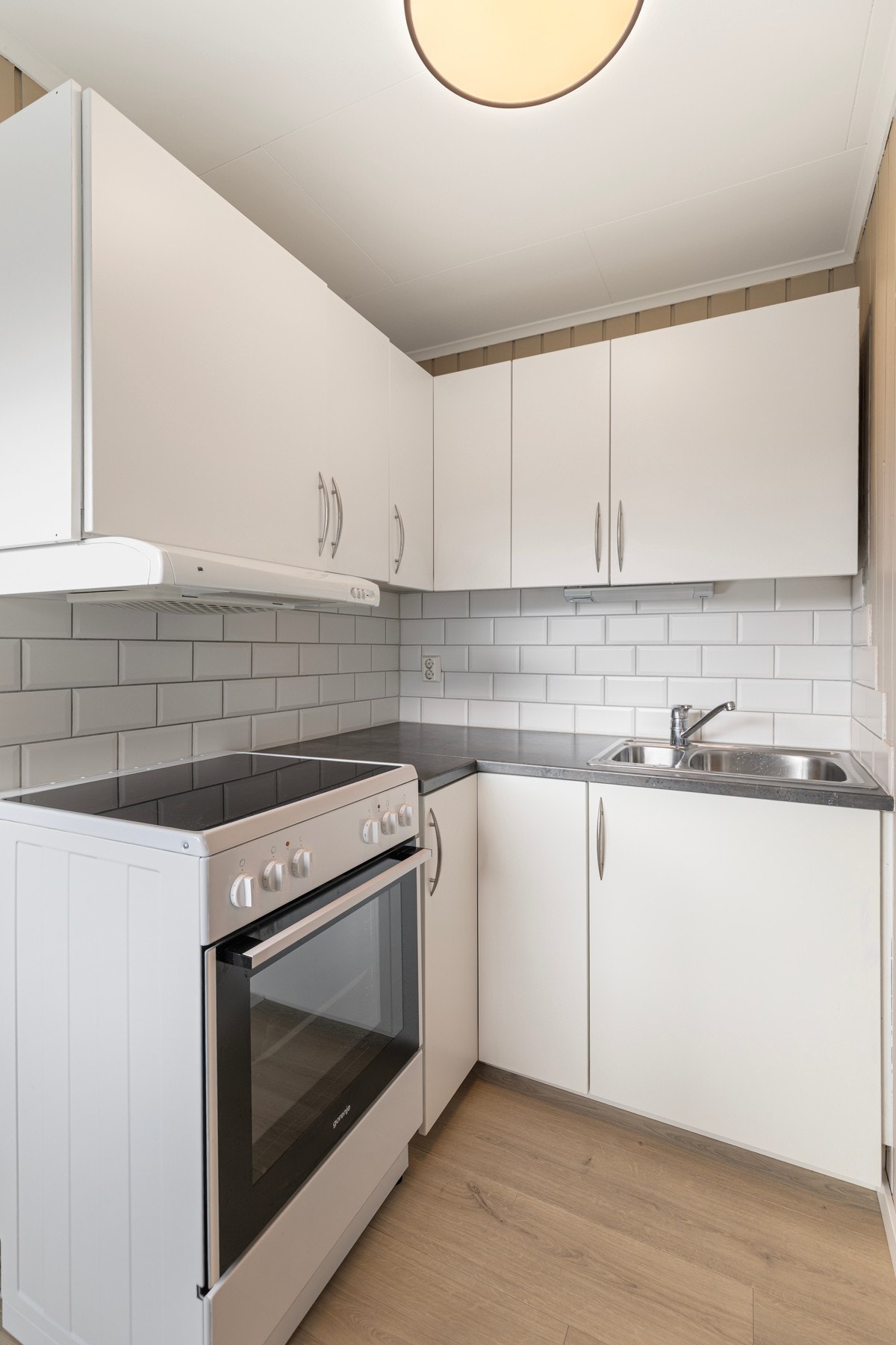 Kjøkkenet har innredning med hvite, slette fronter, laminat benkeplate med flis mot overskapene, ventilator og skyllekum. Galleribilde