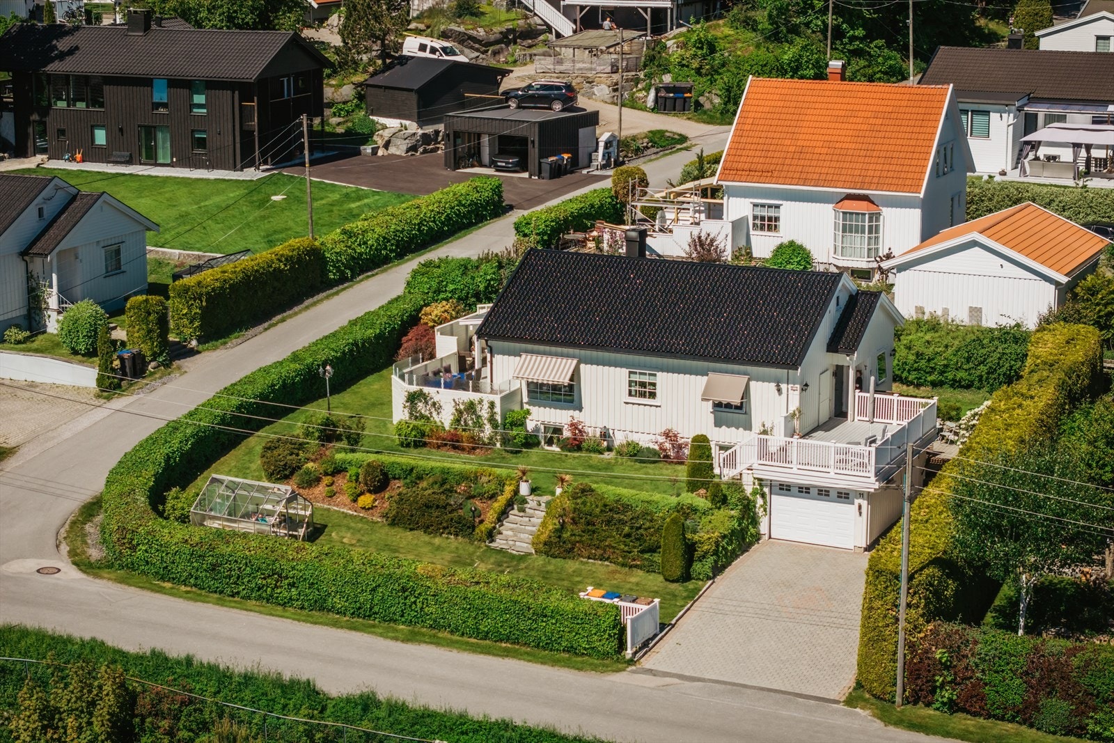 Boligen ligger omkranset av en hekk rundt hele veien, her ser man også hvor fin og oversiktlig hagen er, oppbygget i litt forskjellige platåer. Galleribilde