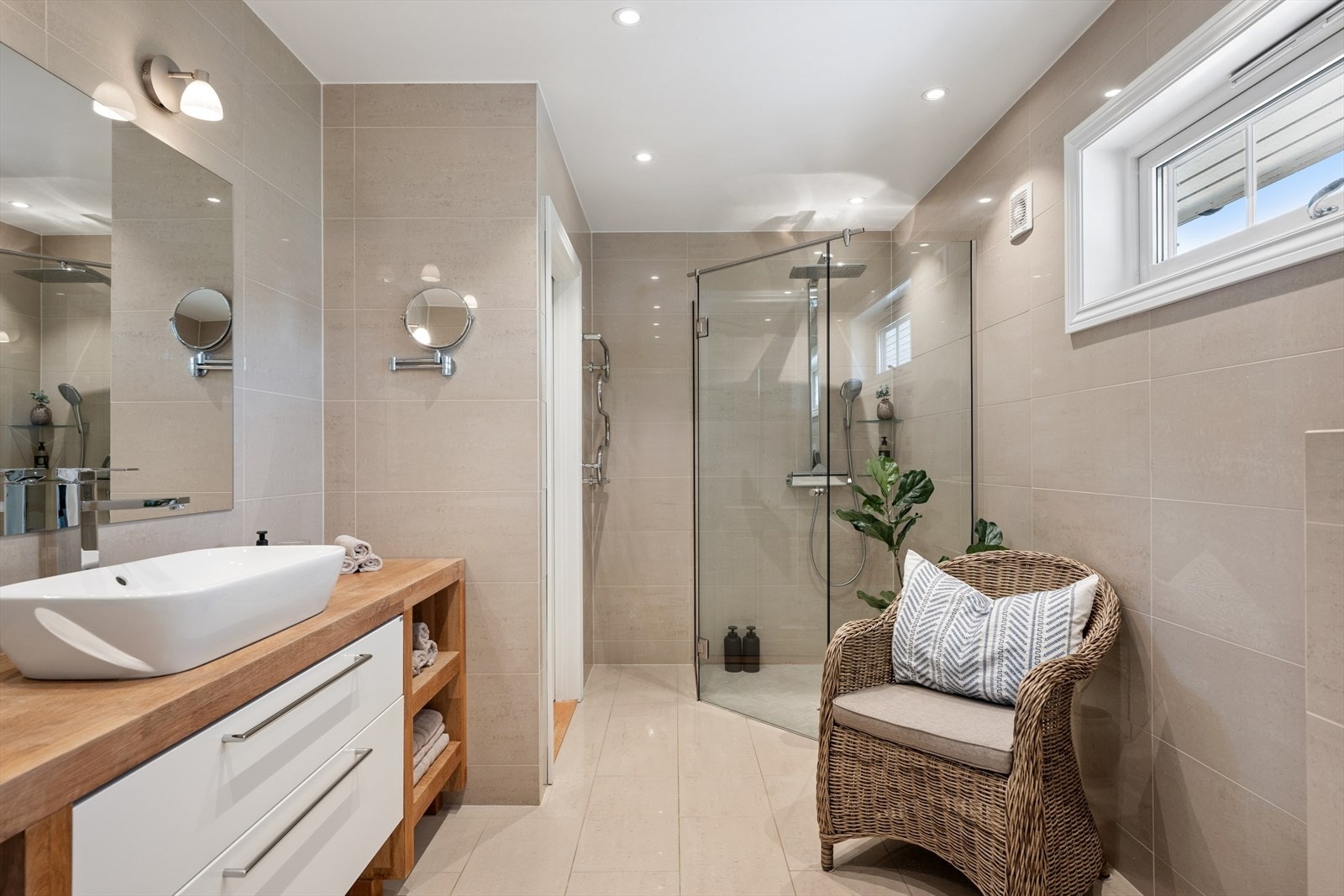 Badet i første etasje er et romslig og elegant bad fra 2010 med lyse fliser, stor dusjsone med glassvegger og innredning med god oppbevaringsplass Galleribilde