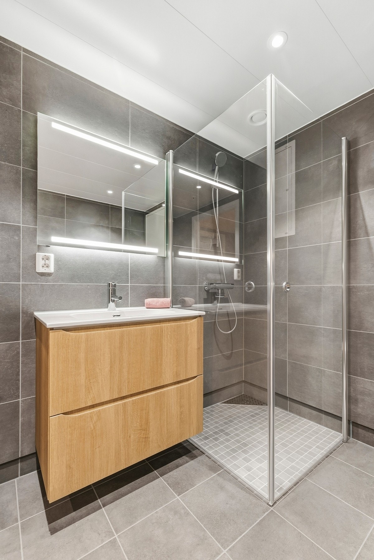 Badet er utstyrt med dusjhjørne med innfellbare dusjdører, samt servantskap med slette fronter i eik. Galleribilde