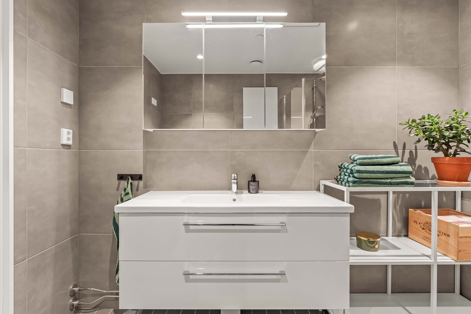 Badet har et stilrent uttrykk med romslig servantinnredning og speilskap som gir gode oppbevaringsmuligheter. Galleribilde