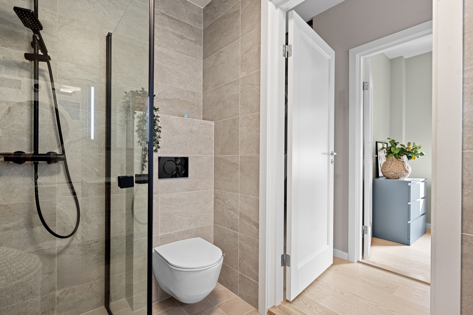 Badet har et stilrent og gjennomført uttrykk med sorte detaljer og romslig dusjsone. Galleribilde