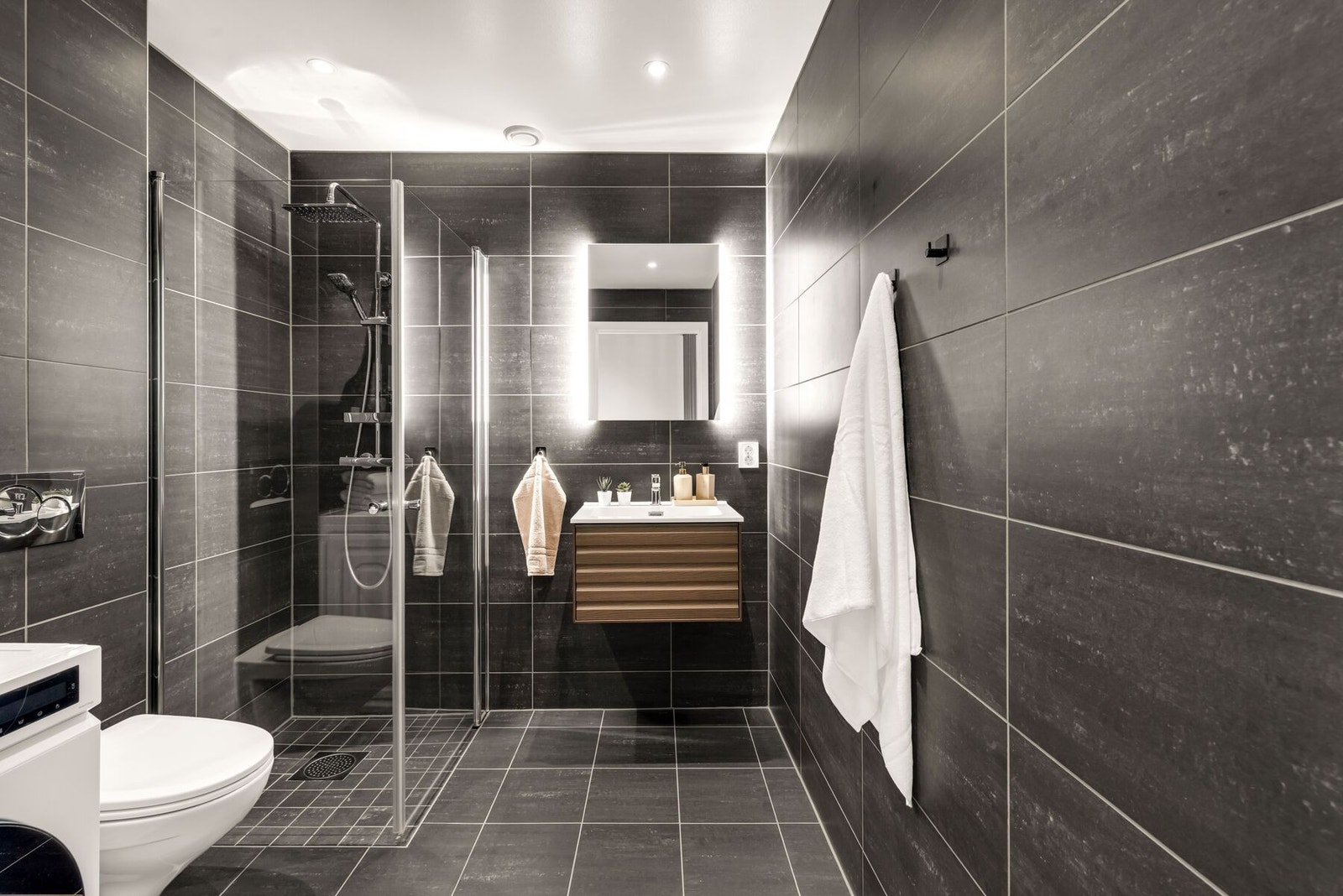 Badet fremstår moderne og innbydende med flislagte overflater og behagelige varmekabler i gulvet. Galleribilde