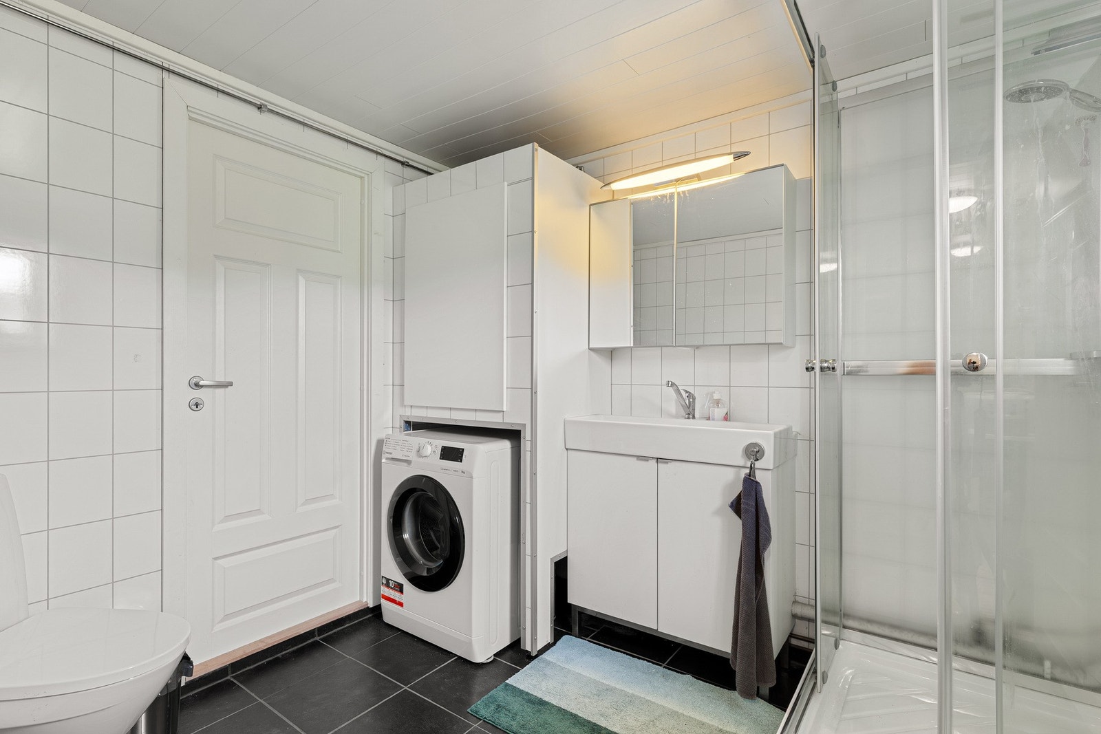 Pent baderom med dusjkabinett og opplegg for vaskemaskin. Galleribilde