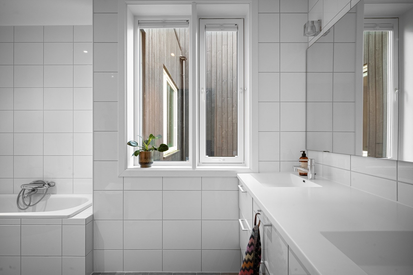 Ett av flere komplette bad med både badekar og dusj. To servanter for enkelt morgen-/og kveldstell. Naturlig lys via vinduer gir det beste sminkelyset. Galleribilde