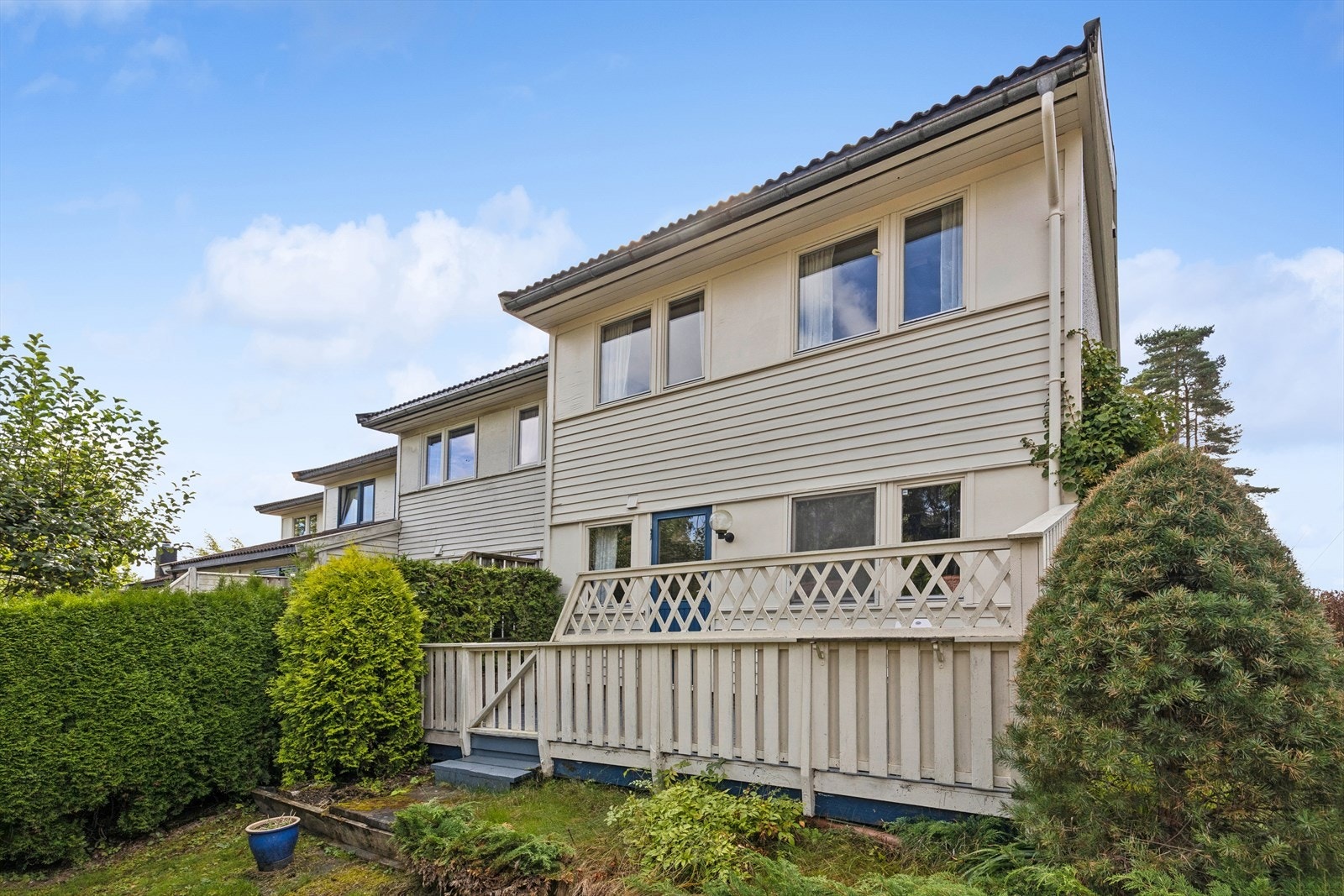 Baksiden av enderekkehuset med terrasse og opparbeidet gressplen. Galleribilde