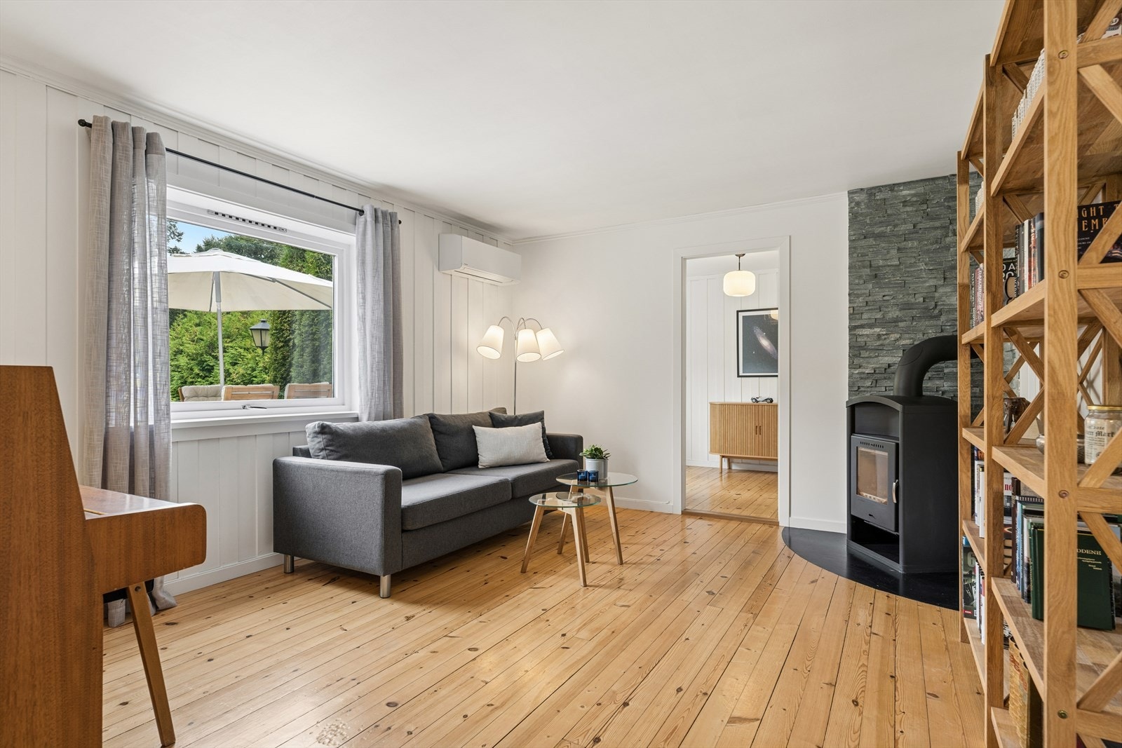 Underetasjen har en egen stue med utsyn mot hagen. Vedovnen med steinforblending setter sitt preg på rommet. Pianoet medfølger handelen og ble sist stemt i 2023. Galleribilde