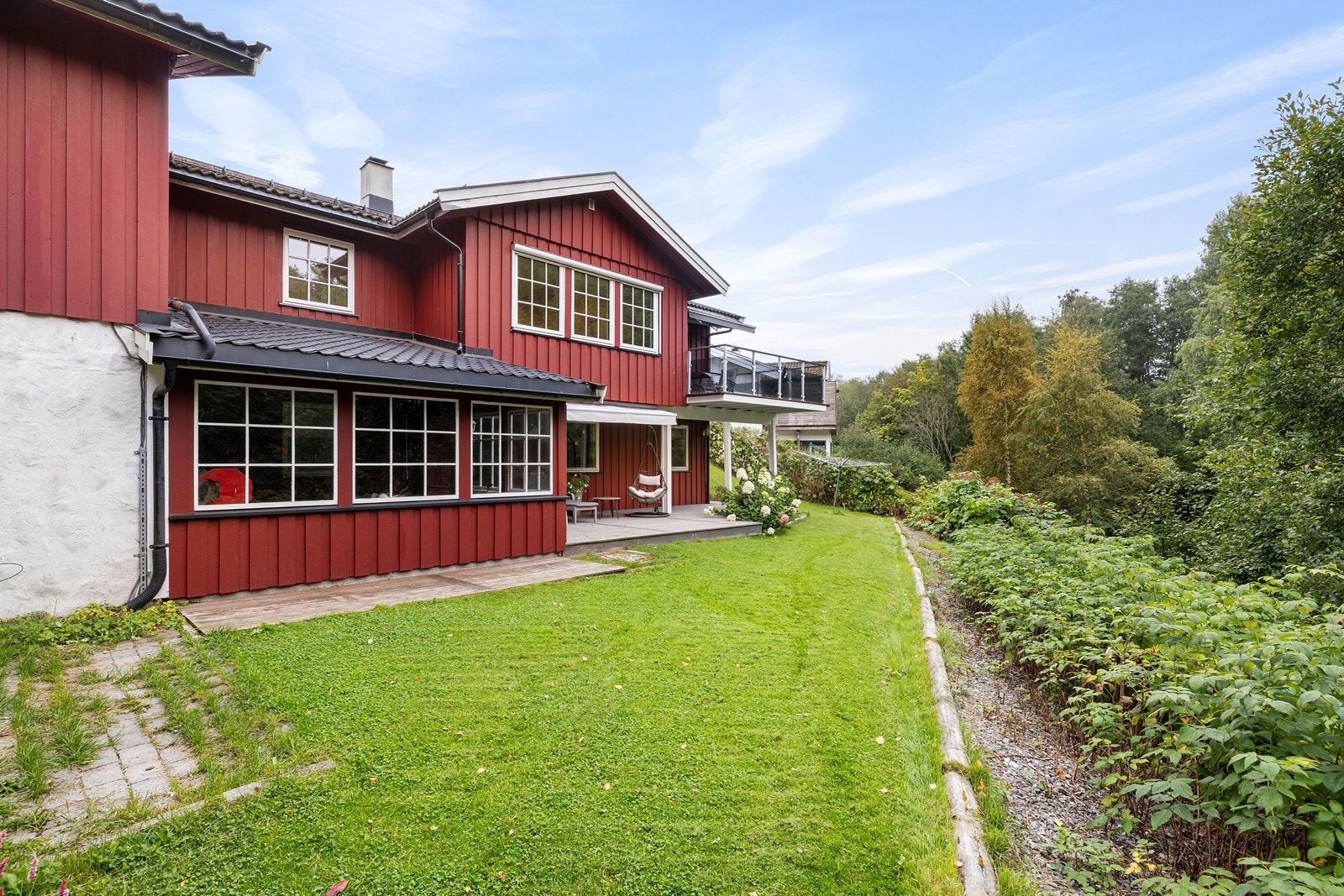 Boligen sett fra hagen - rød fasade, terrasser og grønt område. Galleribilde