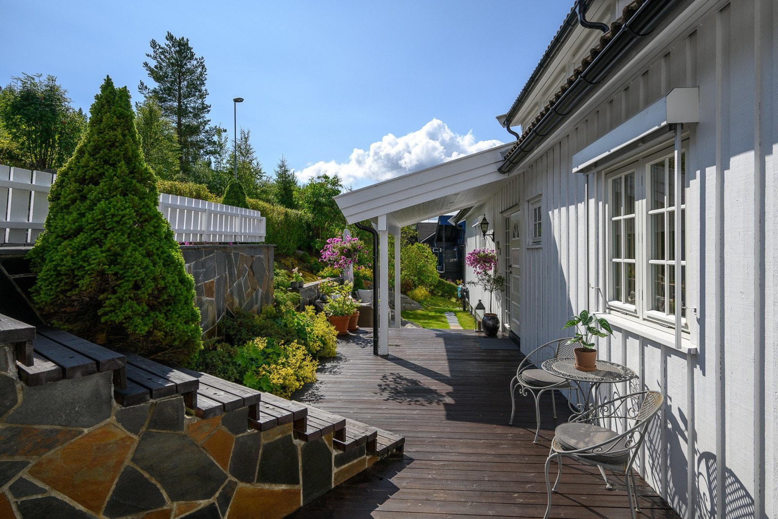 Tomten er pent opparbeidet med plen, beplantning og treterrasser. Galleribilde