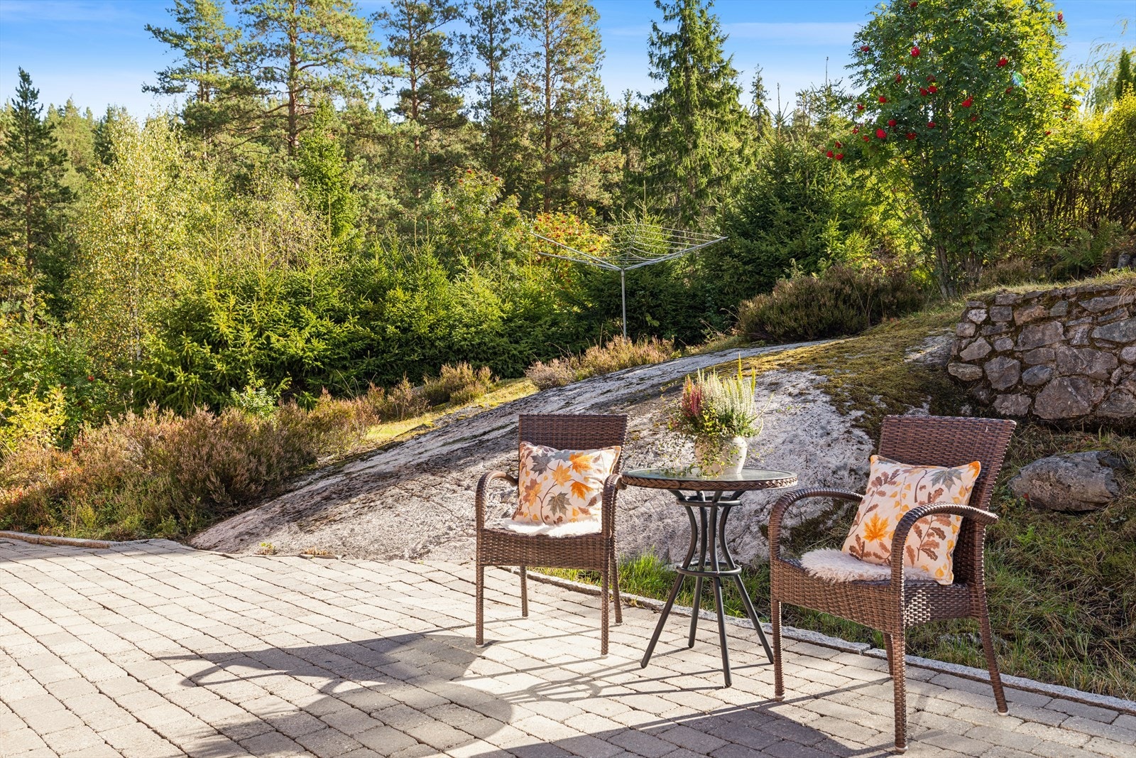 Uteområde med belegningsstein, sitteplass og naturlig fjell i dagen på tomten. Galleribilde