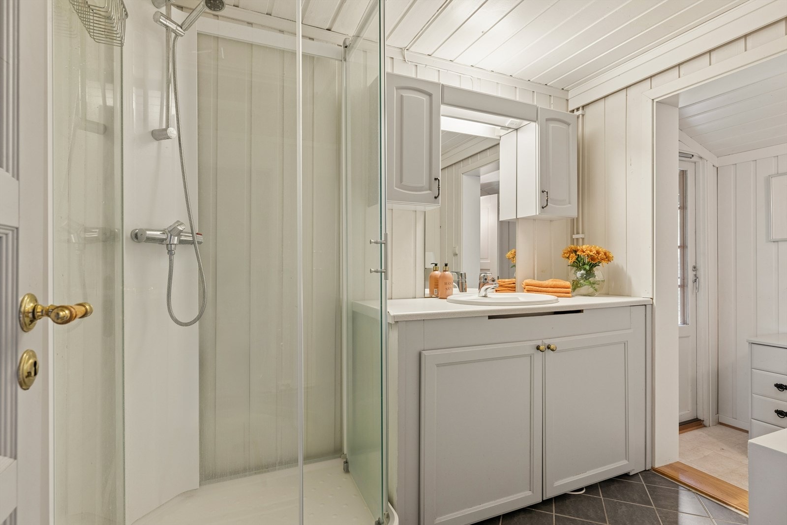 Badet er utstyrt med dusjkabinett og heldekkende servant med underskap. Galleribilde