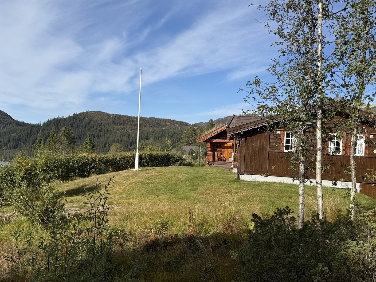 Hekken foran hytta gir gode skjermingsforhold og bidrar til en privat og hyggelig uteplass. Privat foto. Galleribilde