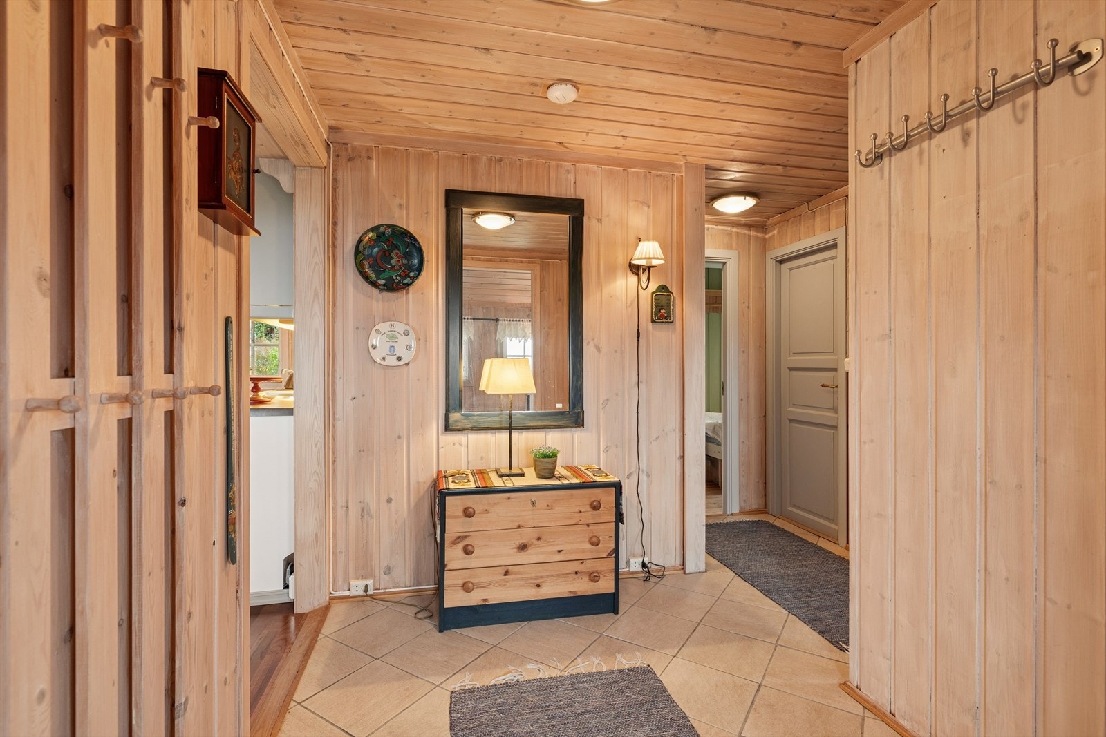 Velkommen inn! Entré og gang med flislagt gulv og plass til klesoppheng og kommode. Galleribilde