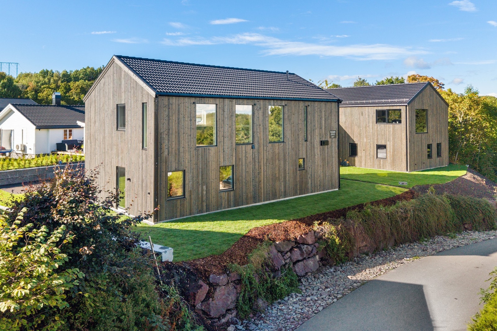 Moderne og stilren bolig med et særpreget arkitektonisk uttrykk, kledd i treverk som gir fasaden et naturlig og eksklusivt preg. Galleribilde