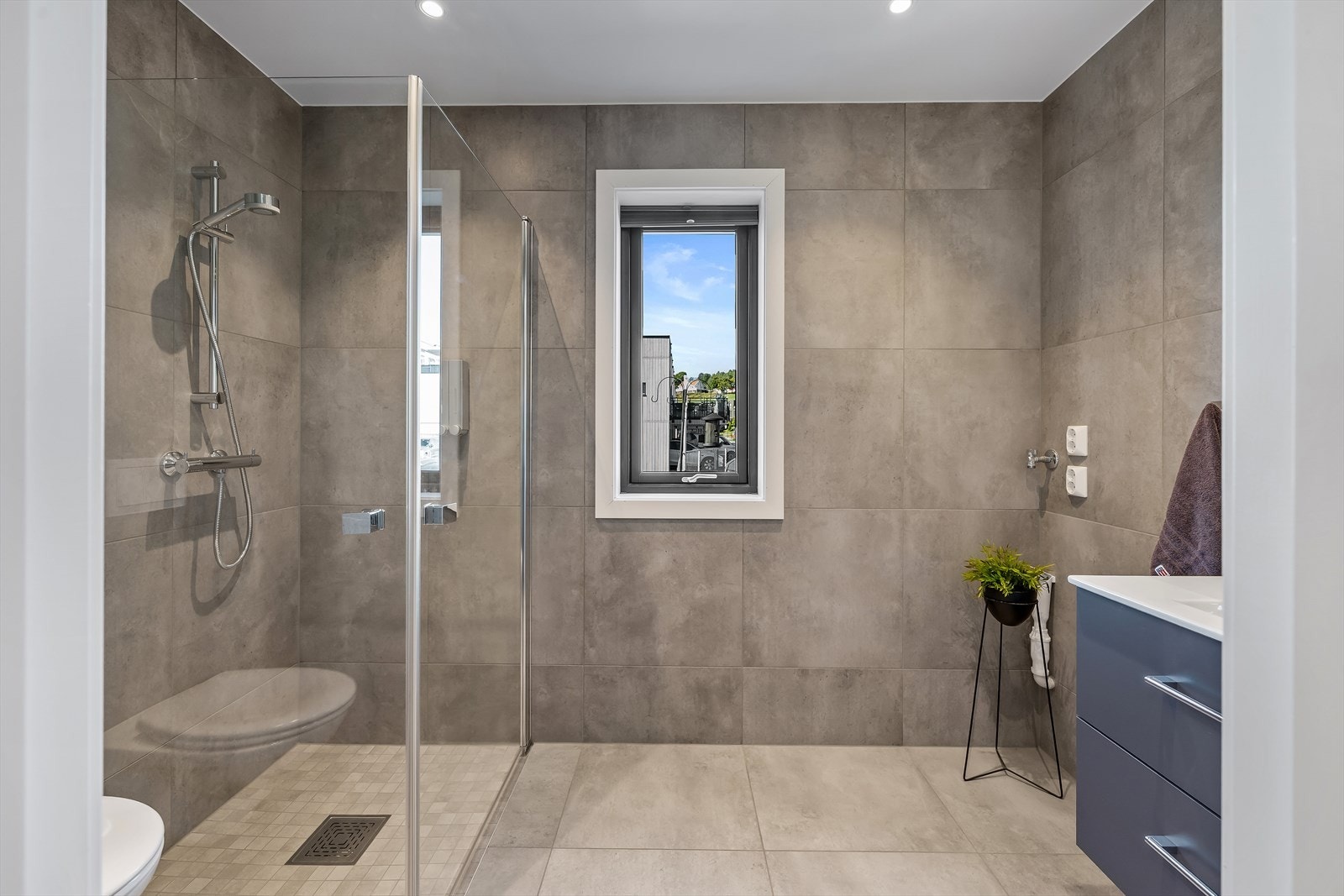 Lekkert og moderne bad med med 60x60 fliser på gulv og vegger med underliggende varme i gulv. Badet er videre utstyrt med heldekkende servant, servantmøblement, dusj m/innfellbare glassdører og vegghengt toalett Galleribilde