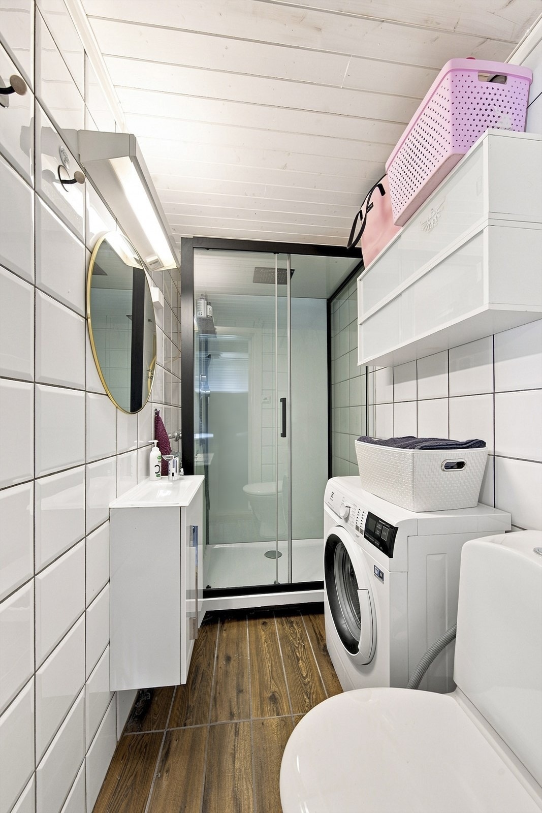 Badet i sidebygget har flislagte vegger og gulv, dusjkabinett og opplegg for vaskemaskin. Galleribilde