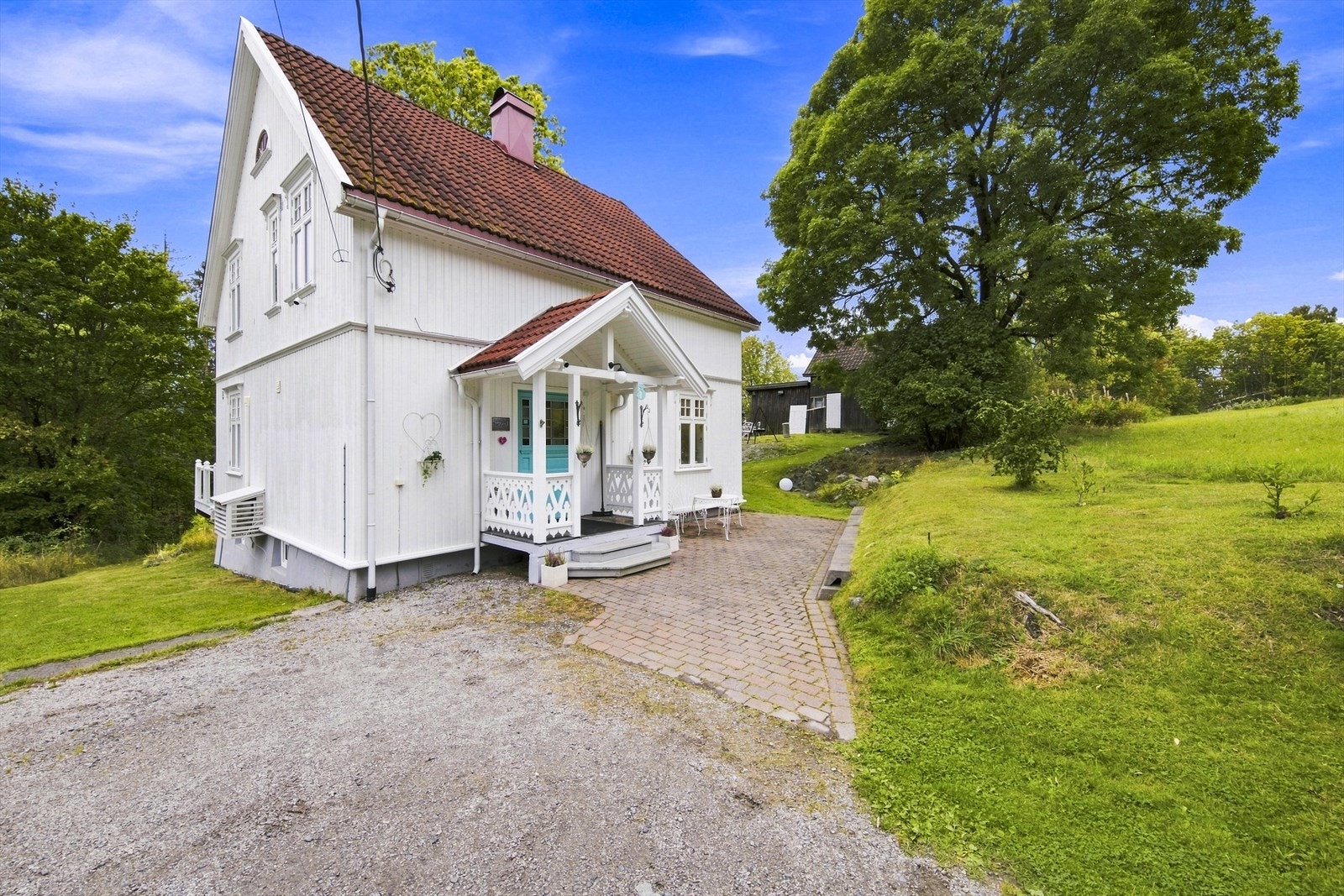 Overbygget inngangsparti med forseggjorte tredetaljer og belegningsstein. Galleribilde