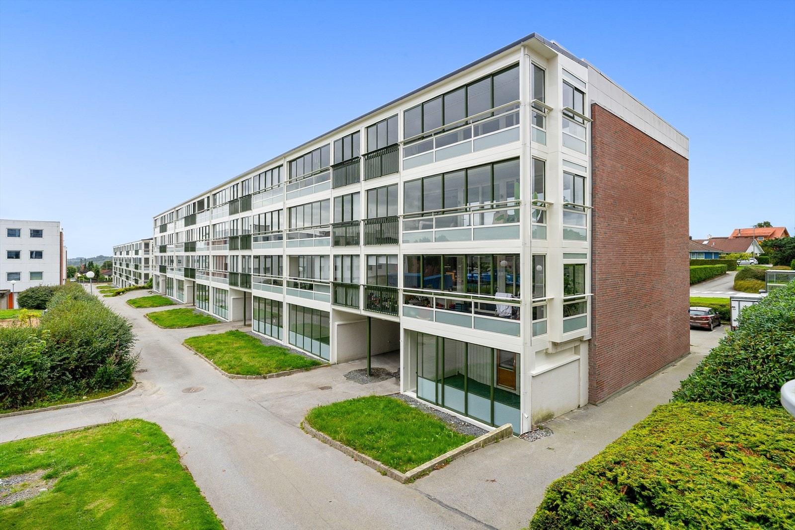 - Boligen ligger på bakkeplan i et etablert boligområde med grønne fellesarealer like utenfor - Galleribilde