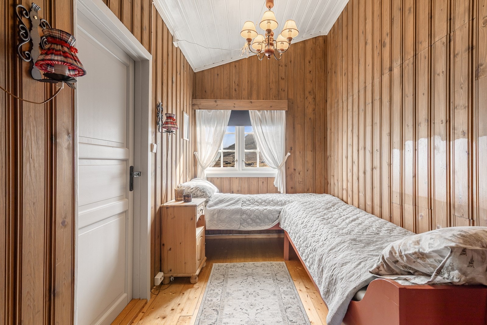 Soverom med den tradisjonelle hyttestilen vidareført gjennom panel og tregolv. Galleribilde
