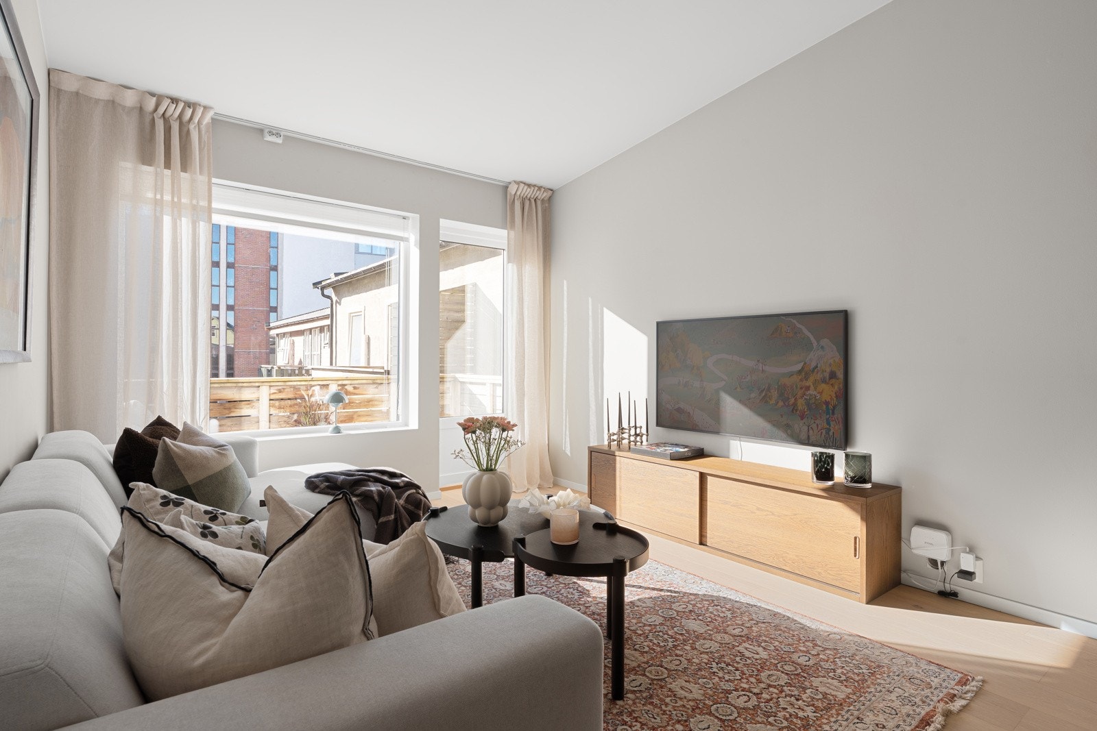 Sofagruppen har sin naturlige plass ved vinduet, med god plass til TV på motsatt vegg. Legg merke til den generøse takhøyden og de store vindusflatene.