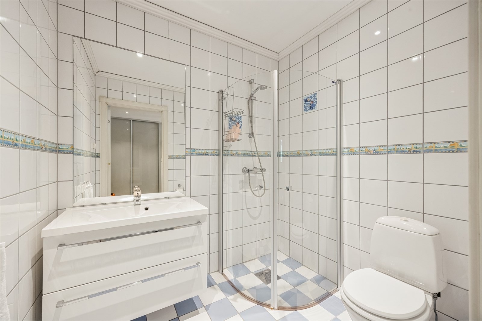 Badet i 1. etasje i hoveddelen er flislagt. Servant med skuffer og dusj med innfellbare dører. Galleribilde
