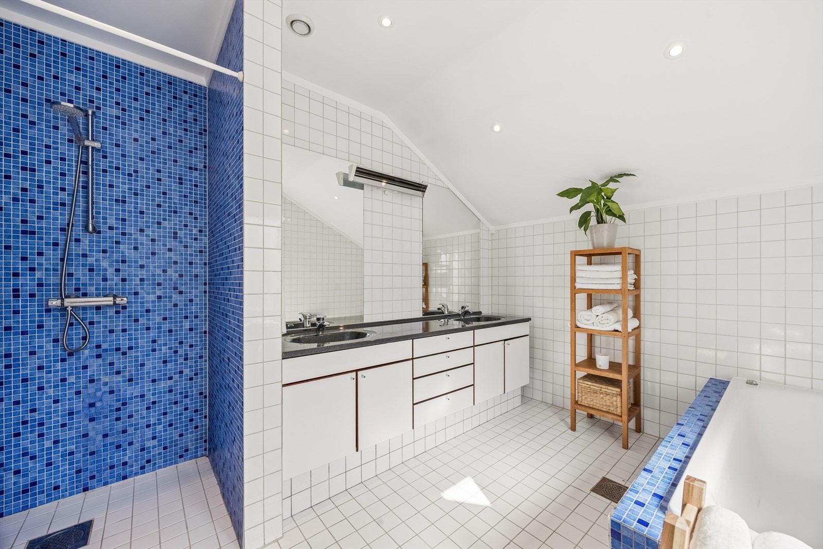 Romslig baderom med dusjnisje, innmurt badekar dobbelservant og godt med skuffer- og skapplss. Downlights i tak. Galleribilde