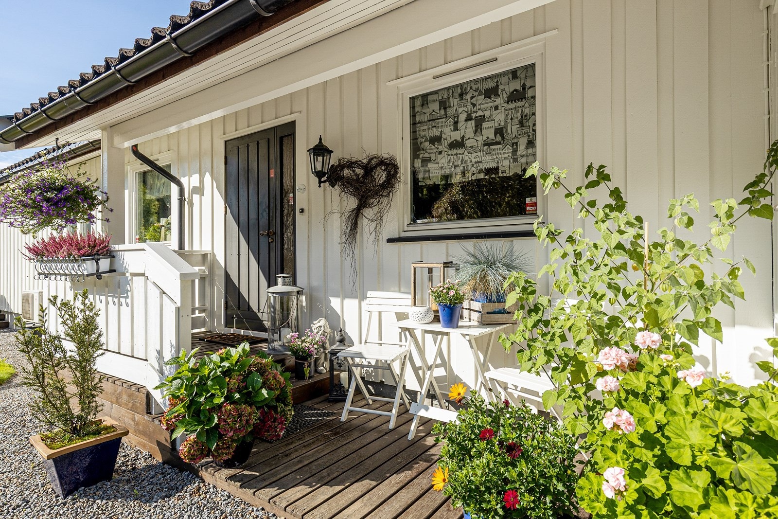 Overbygd inngangsparti med platting av tre med plass til kafesett. Galleribilde