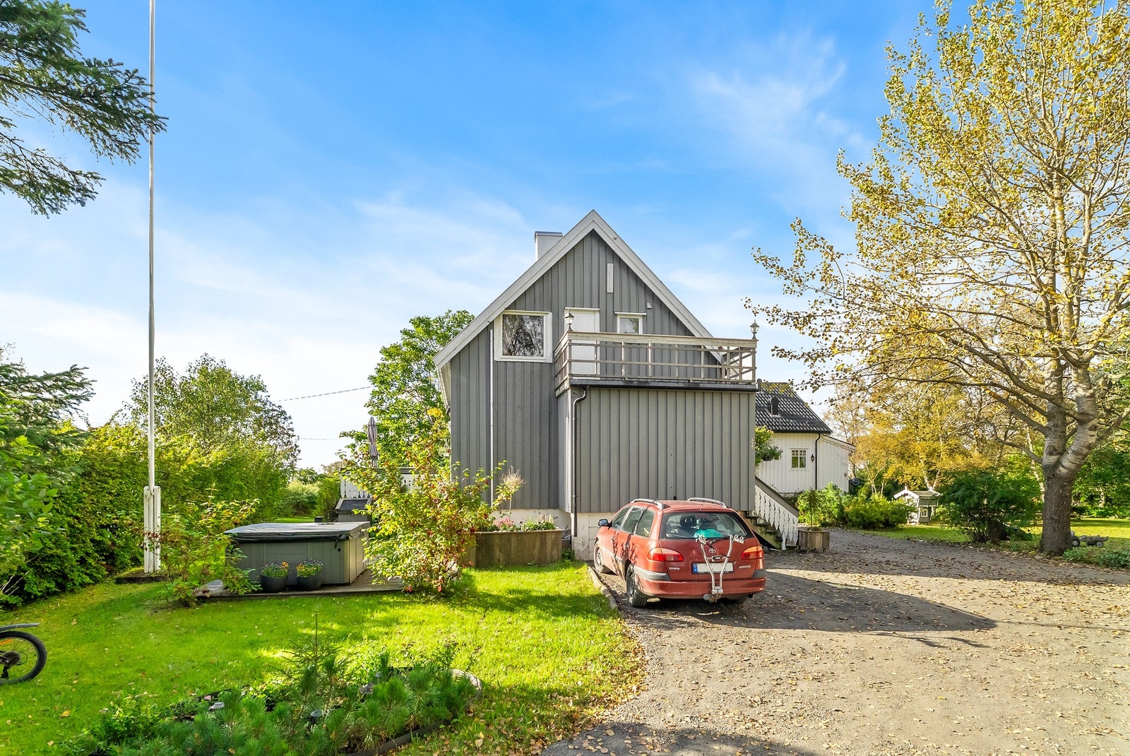 Tverlandsveien 470 med gråmalt kledning, balkong over inngangsparti og gruset gårdsplass. Galleribilde