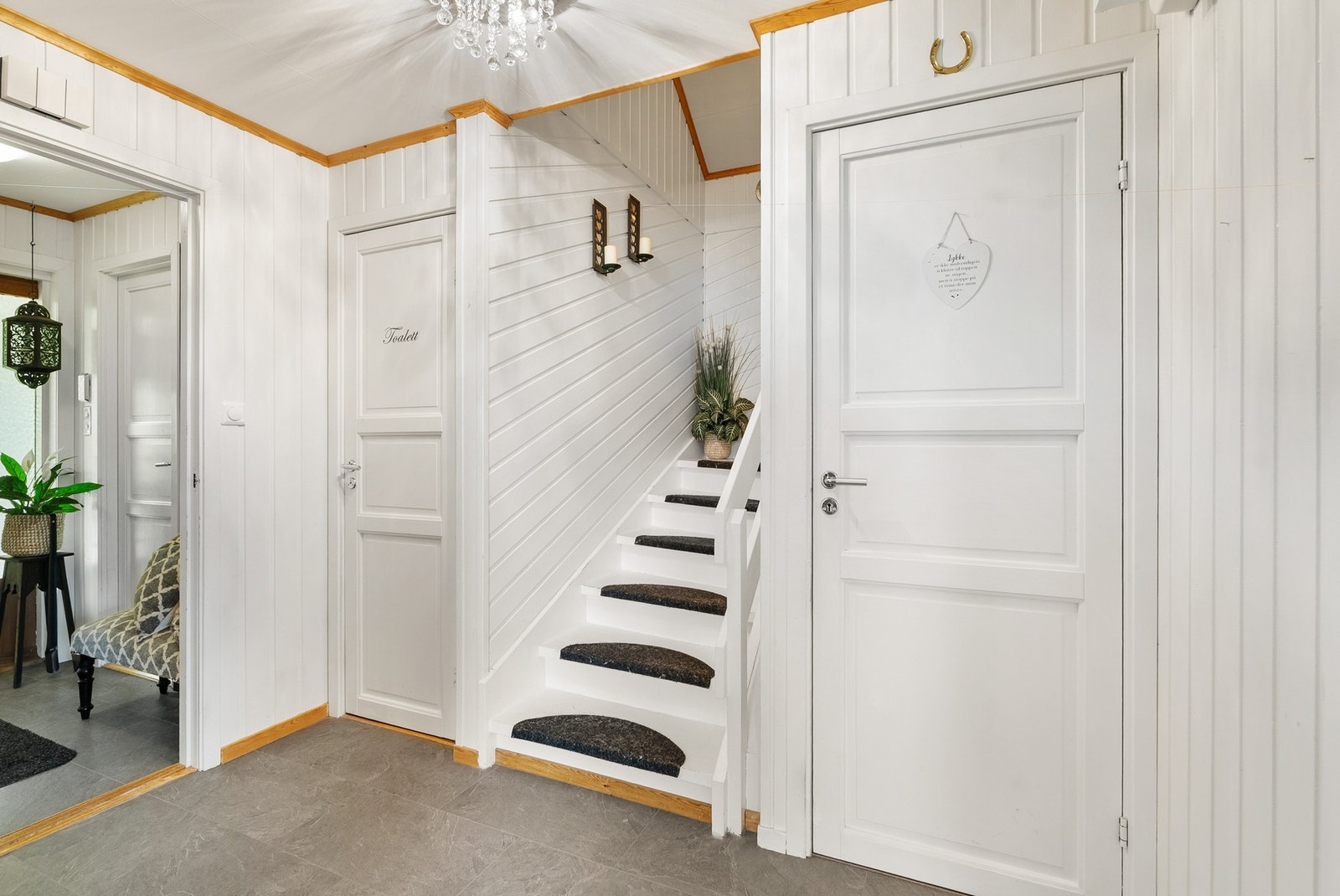 Hvitmalt panel og dør inn til etasjens toalettrom. Galleribilde
