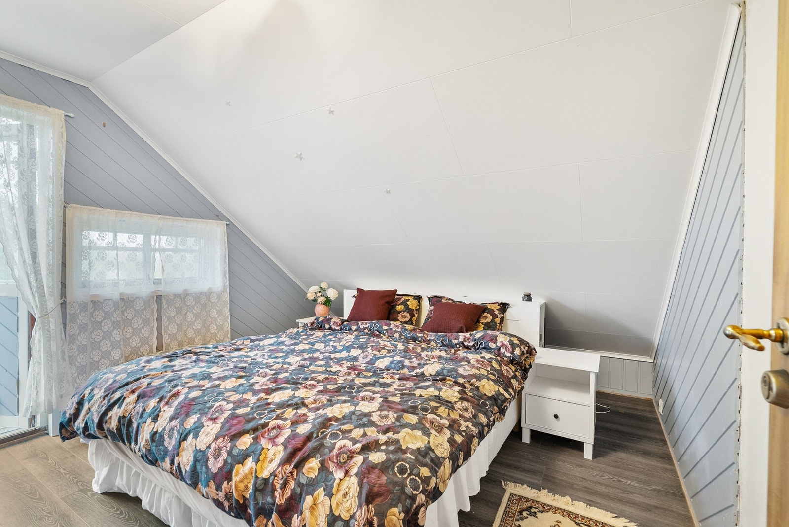 Første soverom i 2. etasje med skråtak, malt panel og god plass til dobbeltseng. Galleribilde
