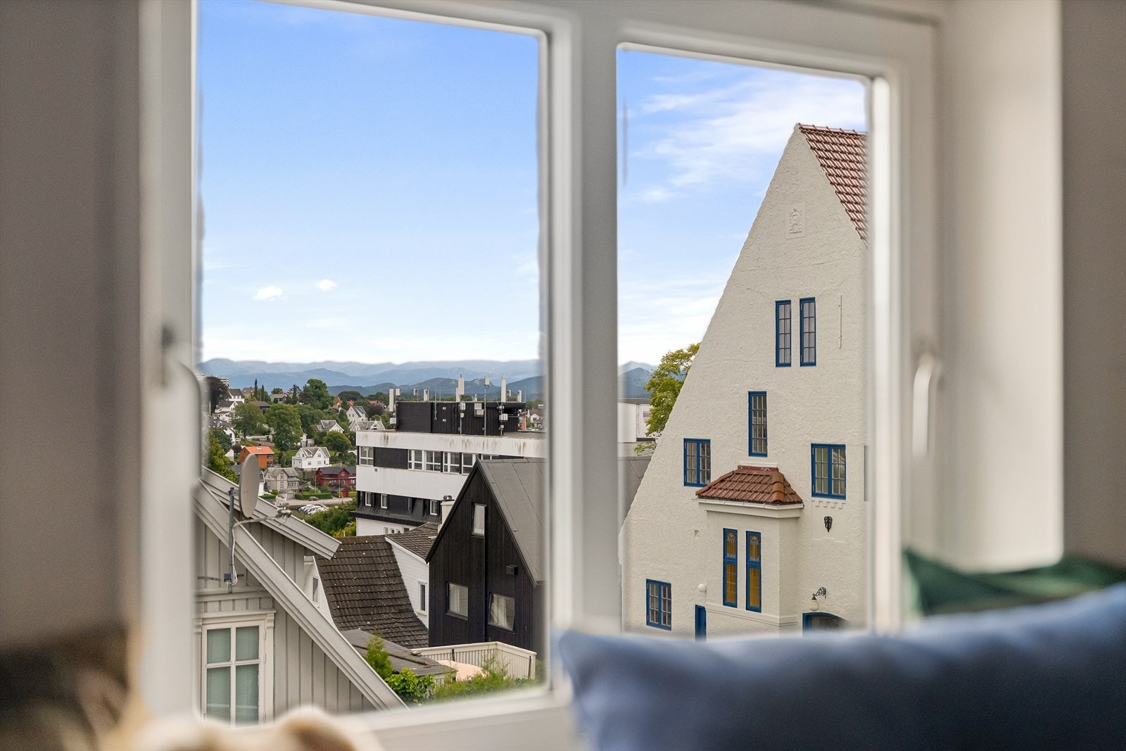 Utsikt over omkringliggende bebyggelse og fjellene i bakgrunnen fra loftsvinduet. Galleribilde
