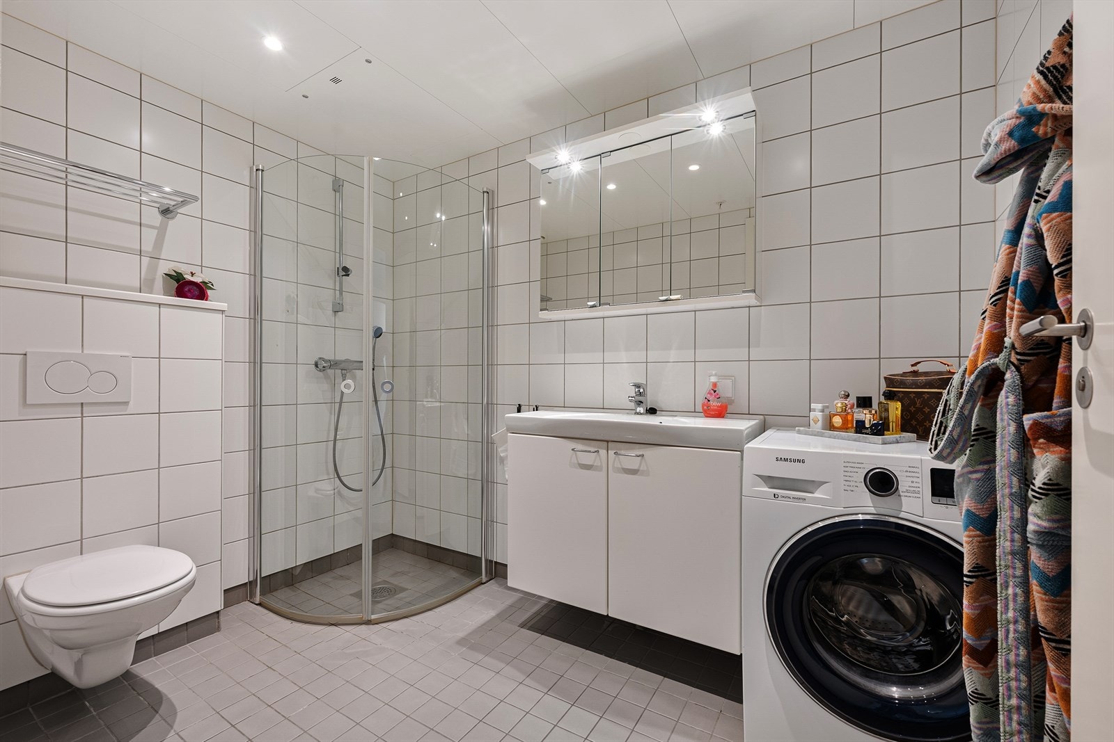 Badet er tidløst innredet med grå fliser på gulvet og hvite fliser på vegg. I gulvet har man også varmekabler for ekstra komfort. Galleribilde