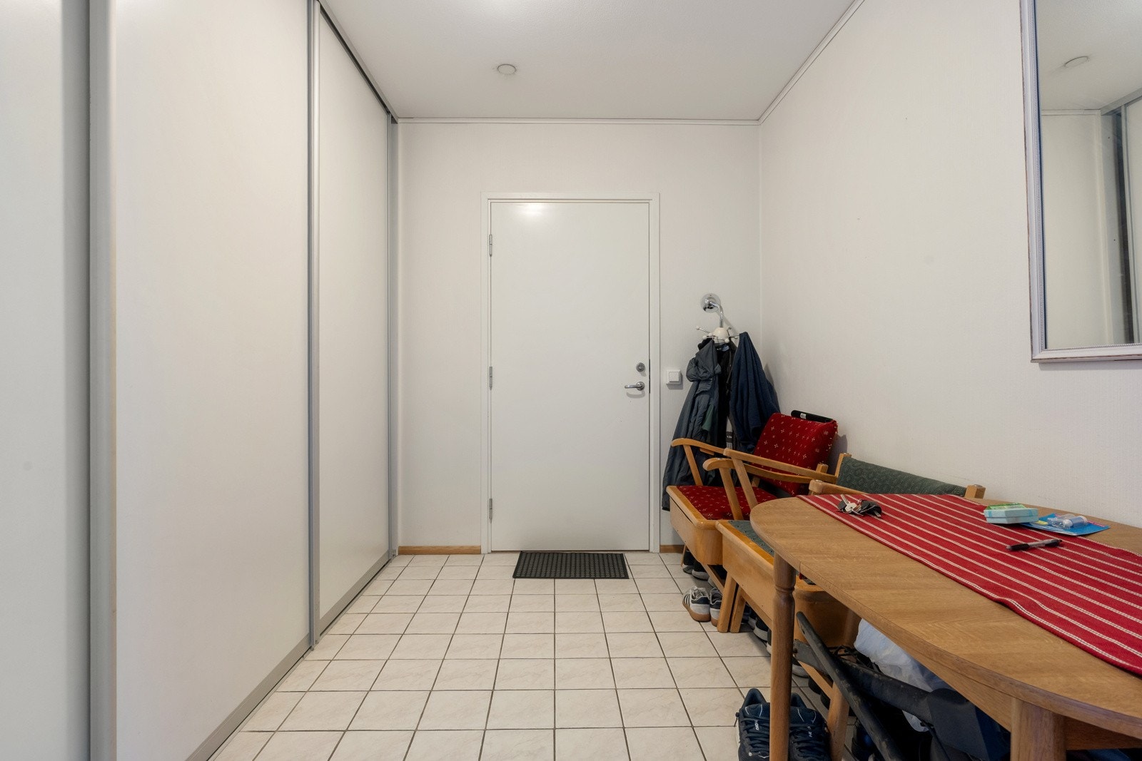 Innbydende entre med fliser på gulv, gulvvarme og skyvedørsgarderobe
