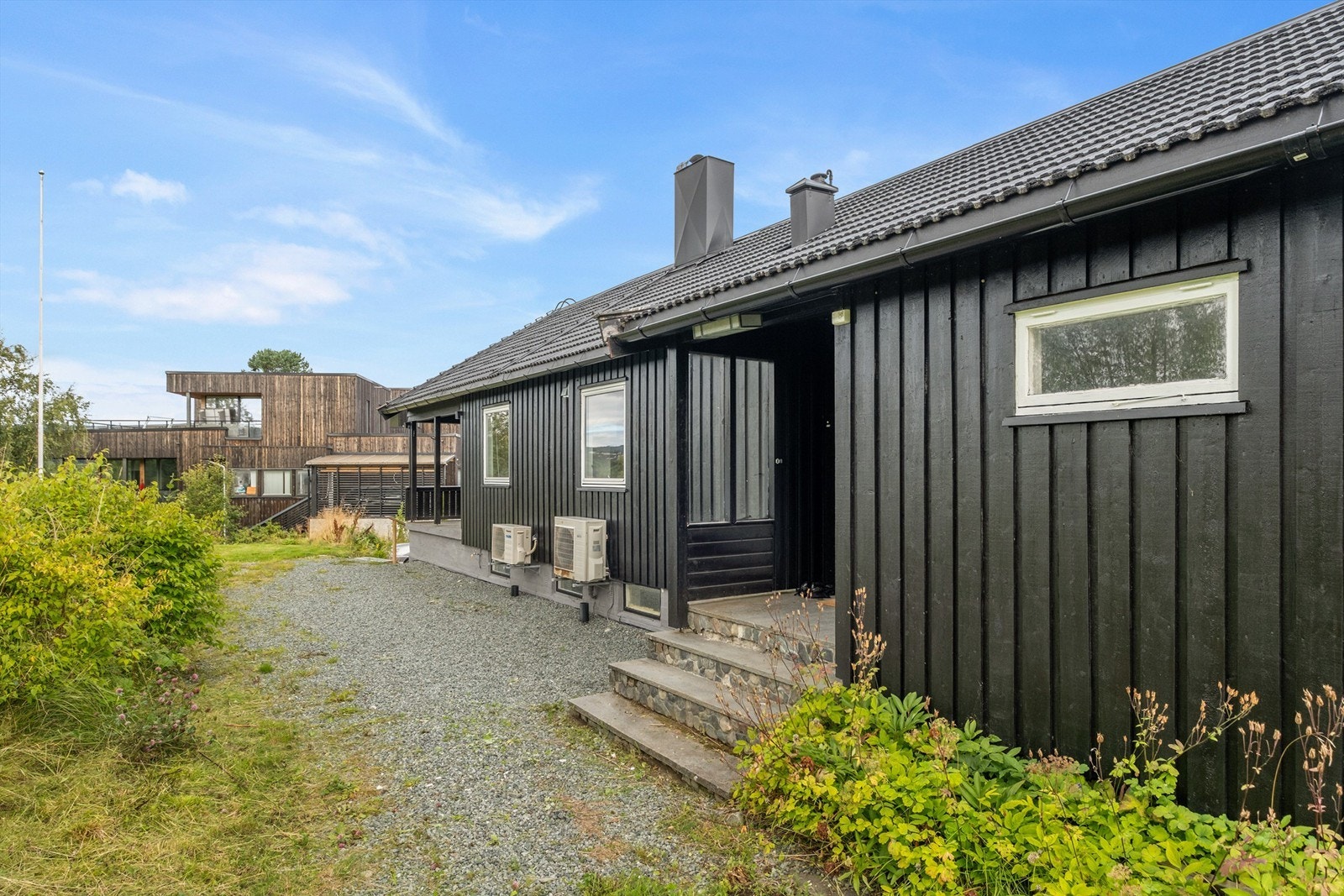 Hovedinngangsparti med steinsatt trapp og adkomst fra gruset gårdsplass. Flere vinduer er skiftet i begge etasjer. Galleribilde
