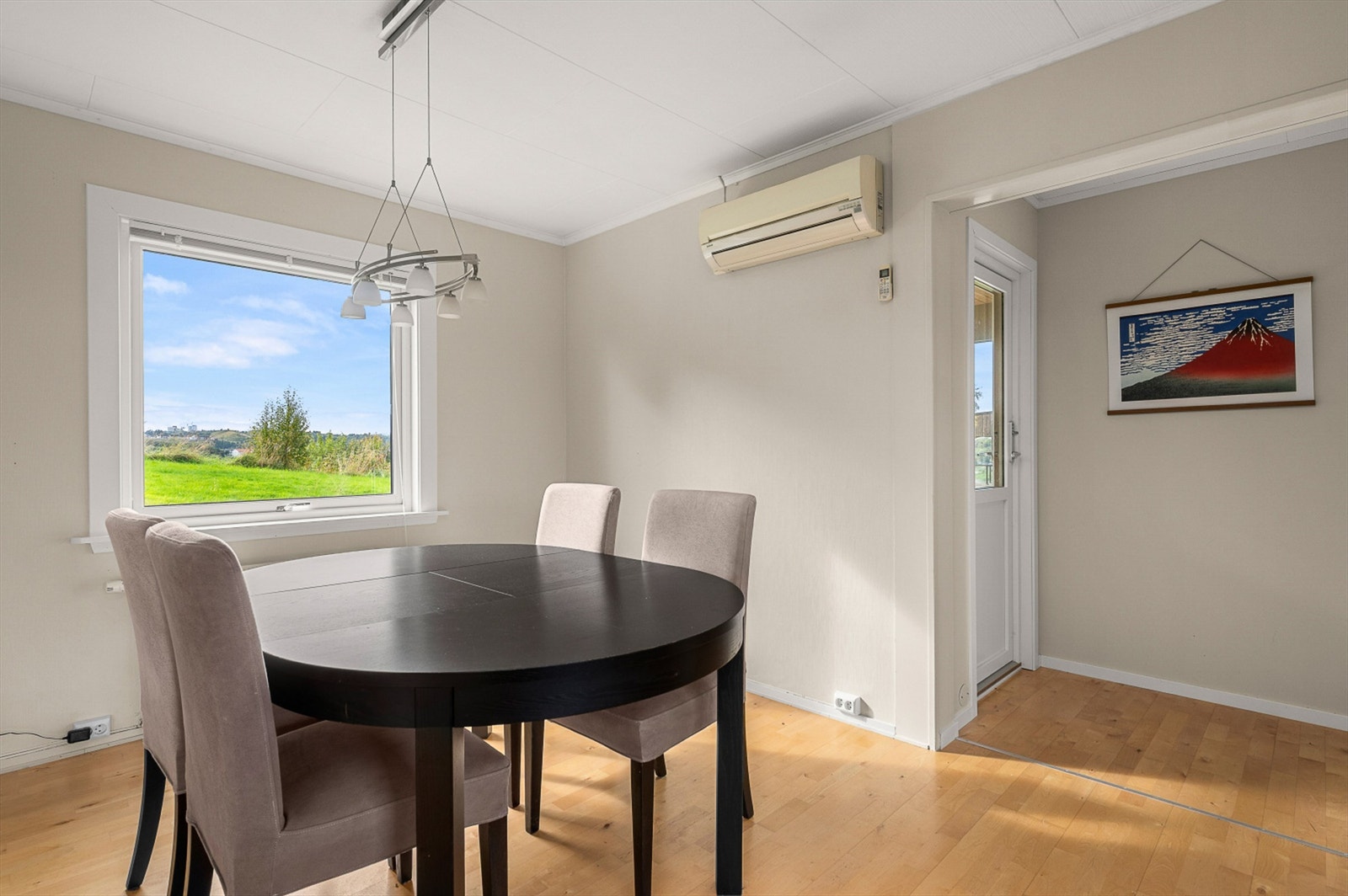 Spiseplass i åpen tilknytning til stuen, plassert like ved kjøkkeninngangen. Vinduet slipper inn rikelig med dagslys og gir utsyn mot hagen. Galleribilde