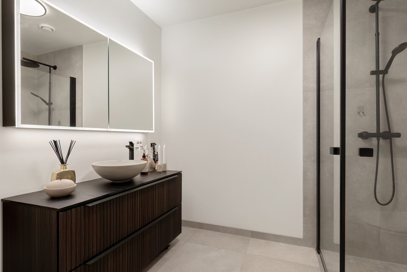 - Også dette badet er lekkert innredet med mørk innredning, speilskap med integrert belysning, dusjhjørne og vegghengt toalett - Galleribilde