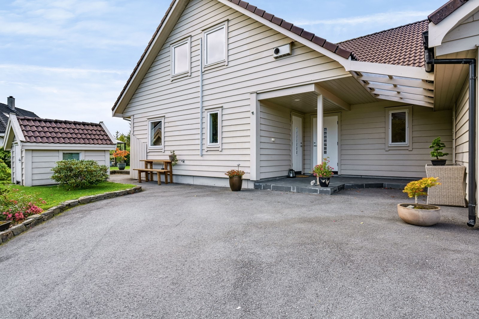 Overbygd inngangsparti og asfaltert gårdsplass med god plass til parkering. Galleribilde
